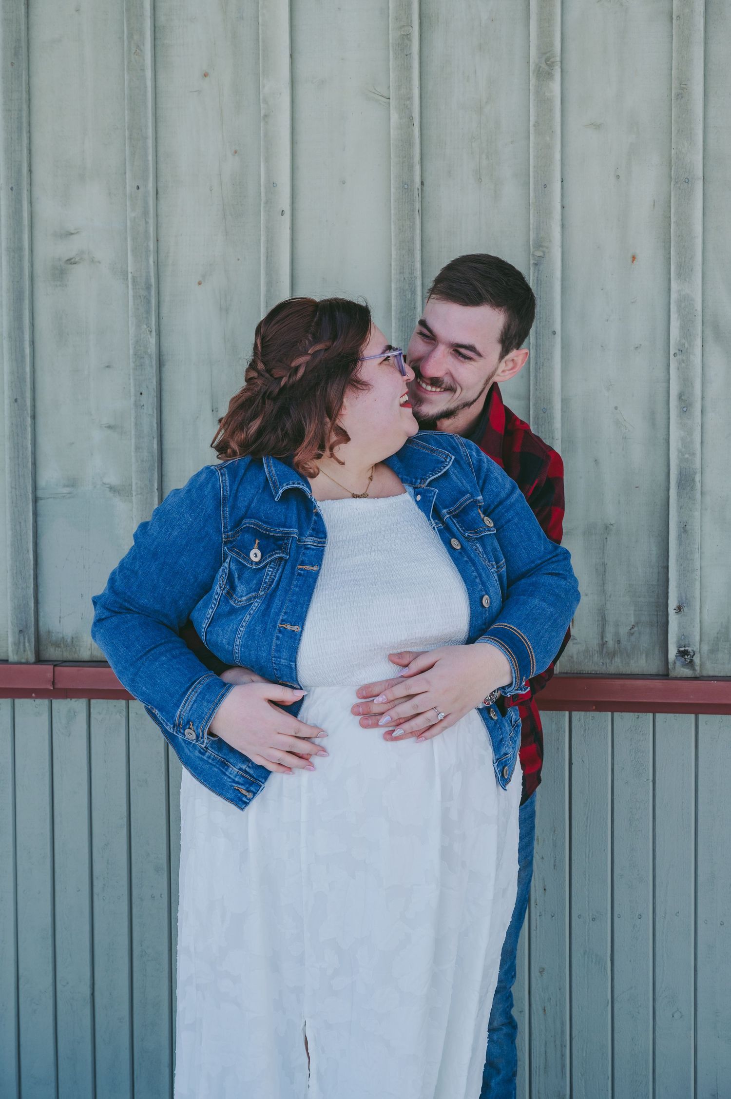 Couple sharing tender moment against industrial wall background.