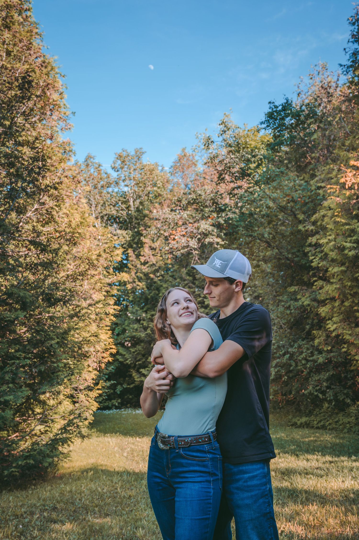 A playful autumn photoshoot scene with golden trees and blue sky in the background.