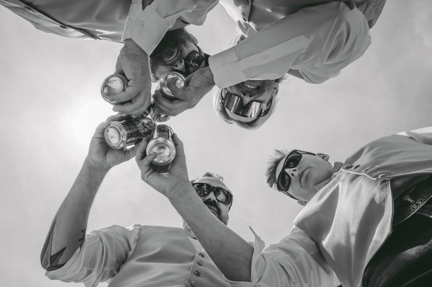 Low angle black and white shot of a celebratory toast with raised glasses.