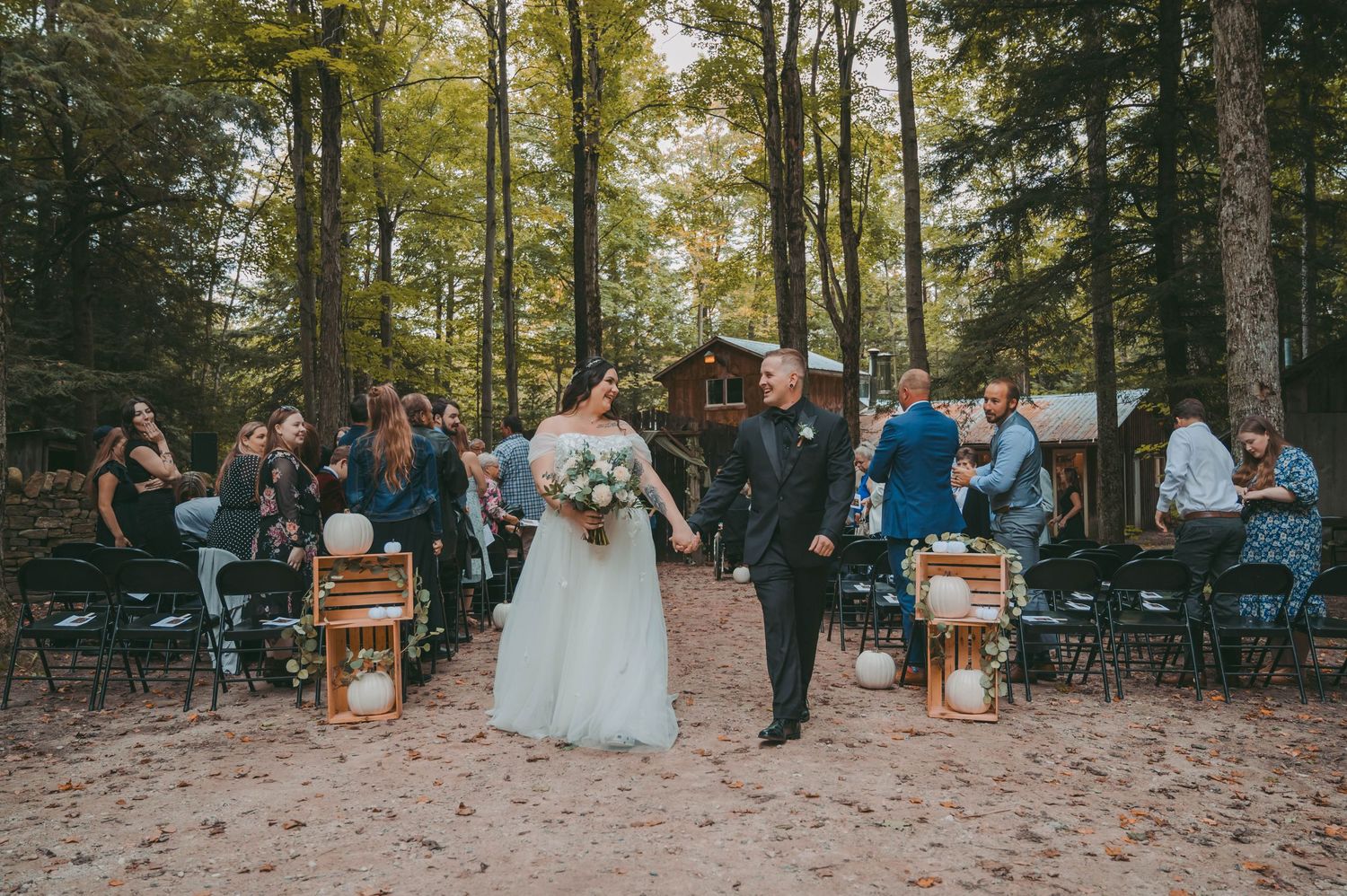 Newlyweds walk down the aisle in a forest wedding ceremony setting.