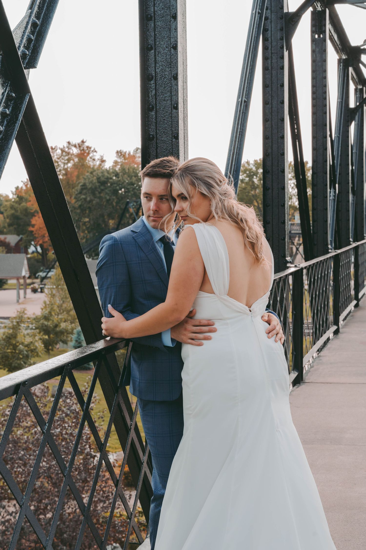 Wedding couple sharing intimate moment on rustic metal bridge.
