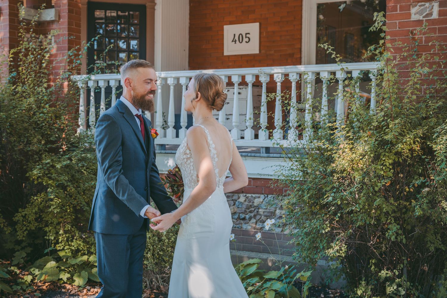 Couple holds hands during first look moment in garden of historic building.