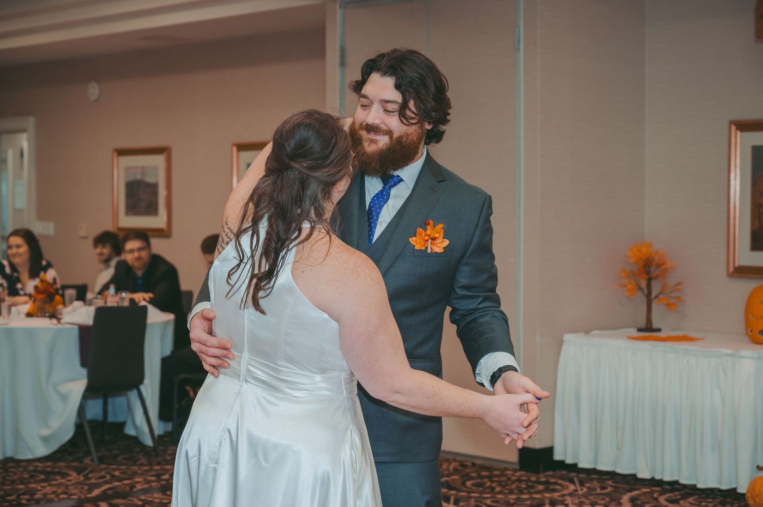 A candid moment of a couple dancing at their wedding reception with decorative fall decor.