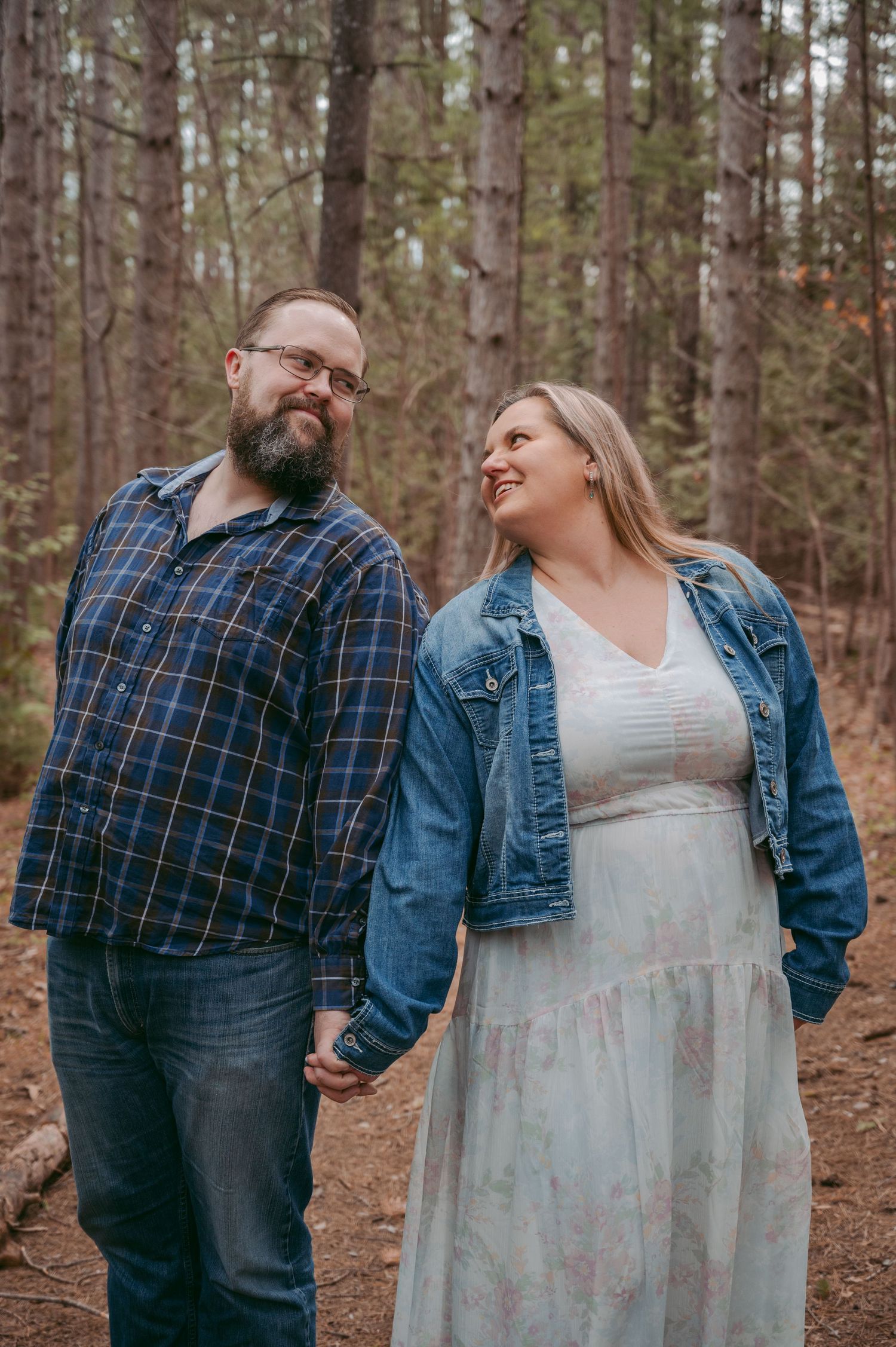 Couple laughing together on forest trail wearing casual attire.