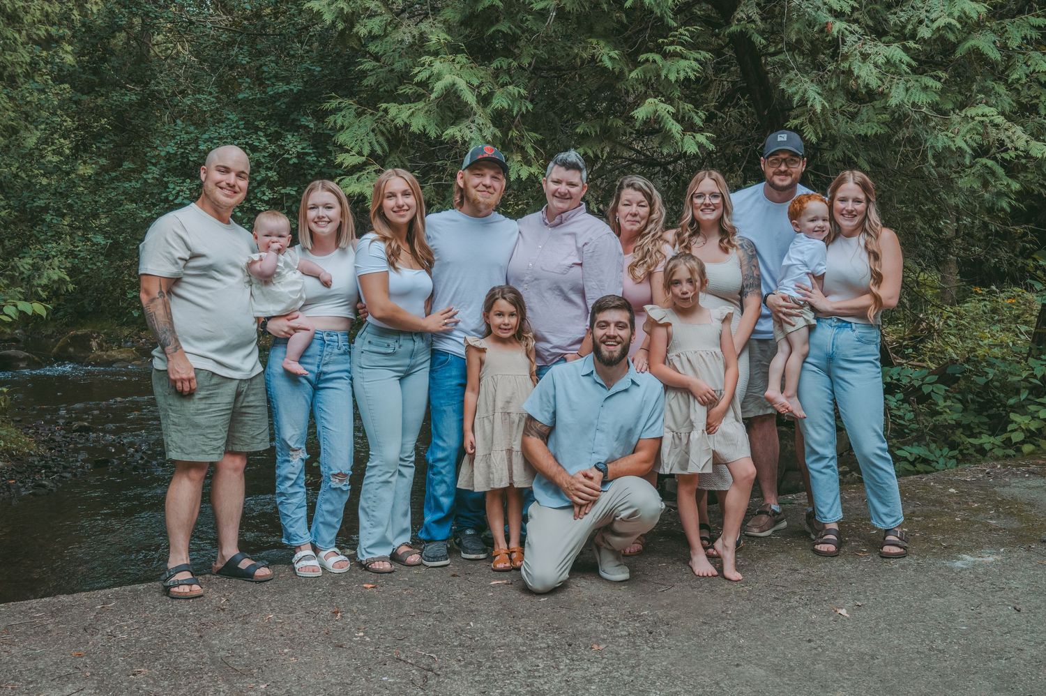 Large family group posed together outdoors near a stream.