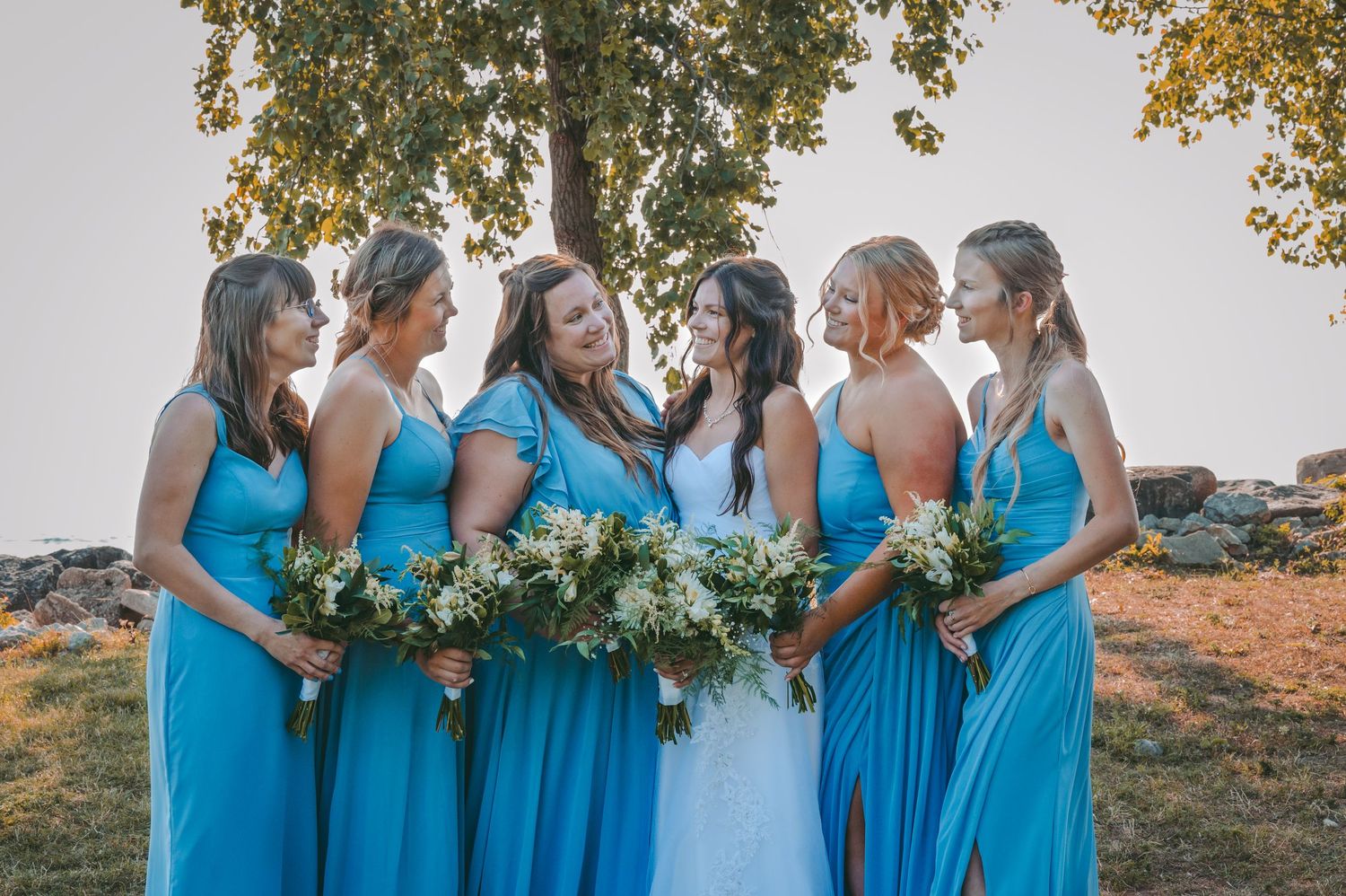 Bridesmaids in matching turquoise dresses share a joyful moment with bride.