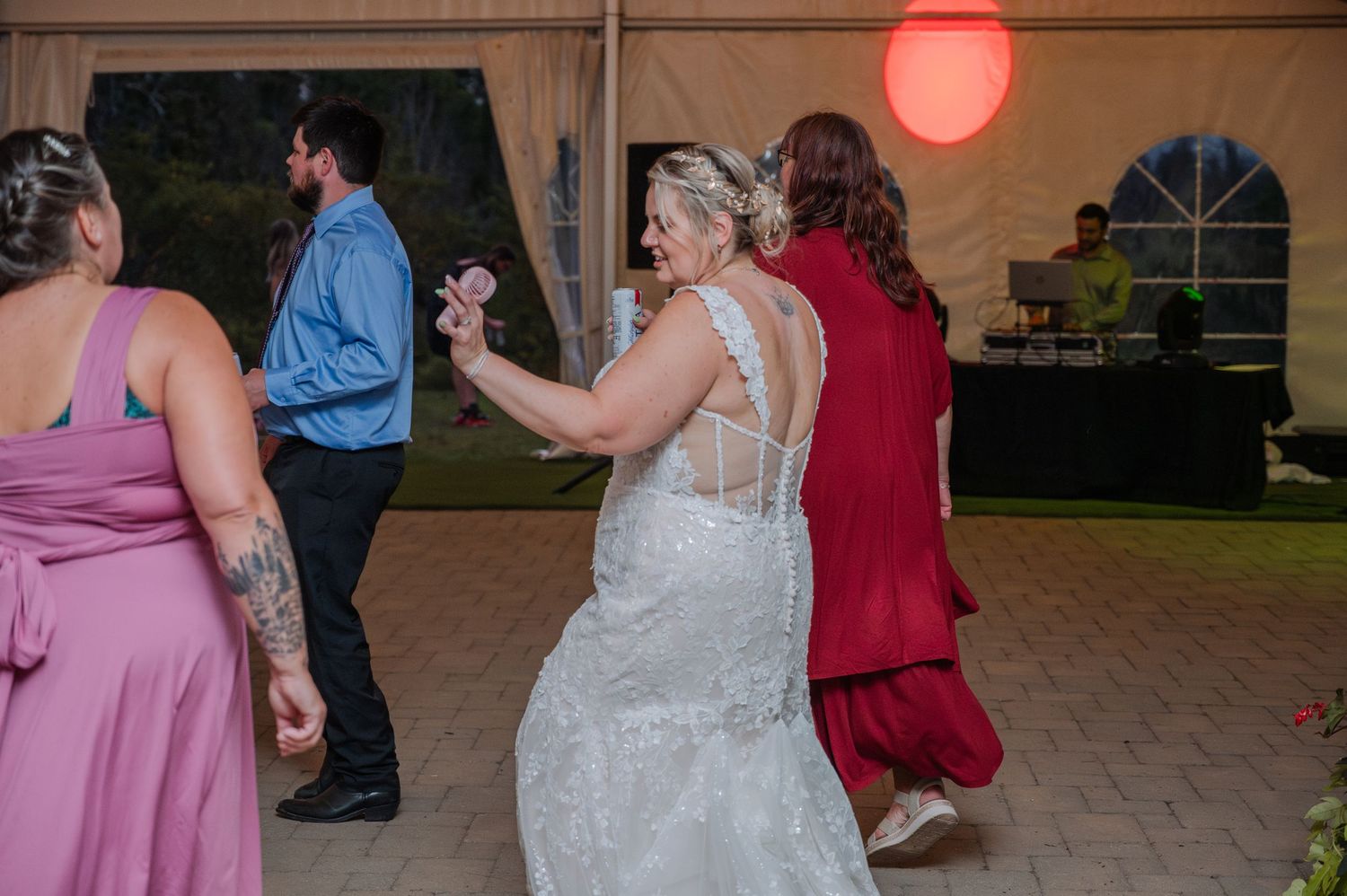 Wedding guests dance together on an outdoor patio during an evening reception celebration.