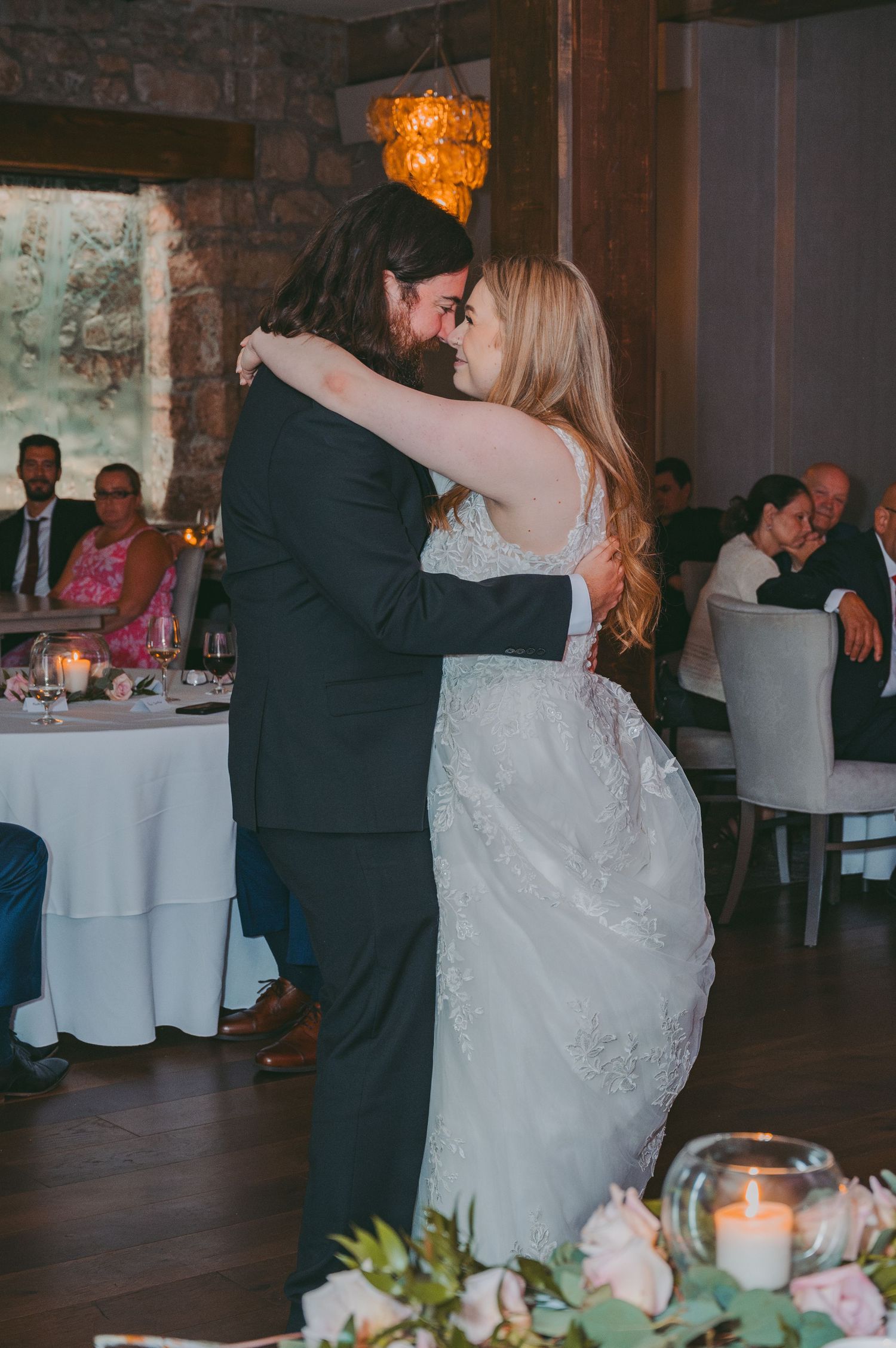 A couple shares their first dance at a romantic reception with candlelit tables.