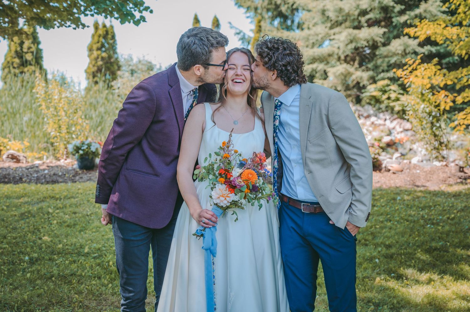 Group photo with bride holding colorful bouquet in outdoor garden setting.