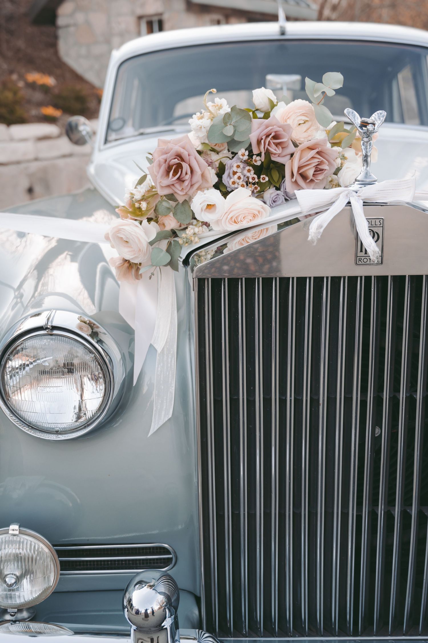 Vintage Rolls Royce luxury car decorated with blush pink roses and white flowers for a wedding.