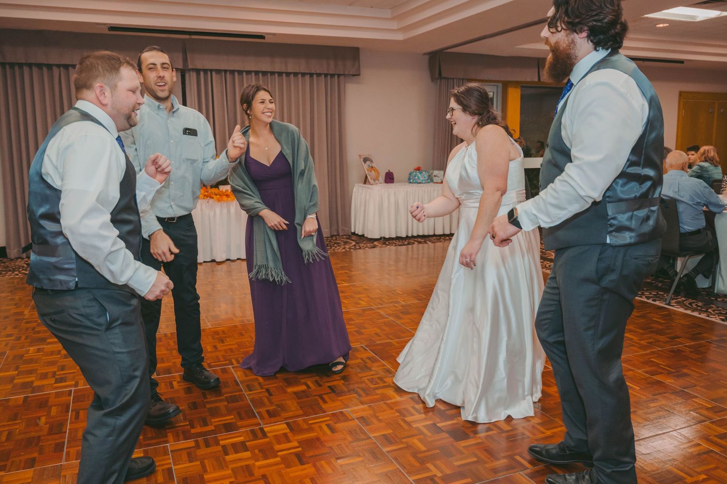 Wedding party dancing and celebrating on wooden dance floor with autumn decorations.