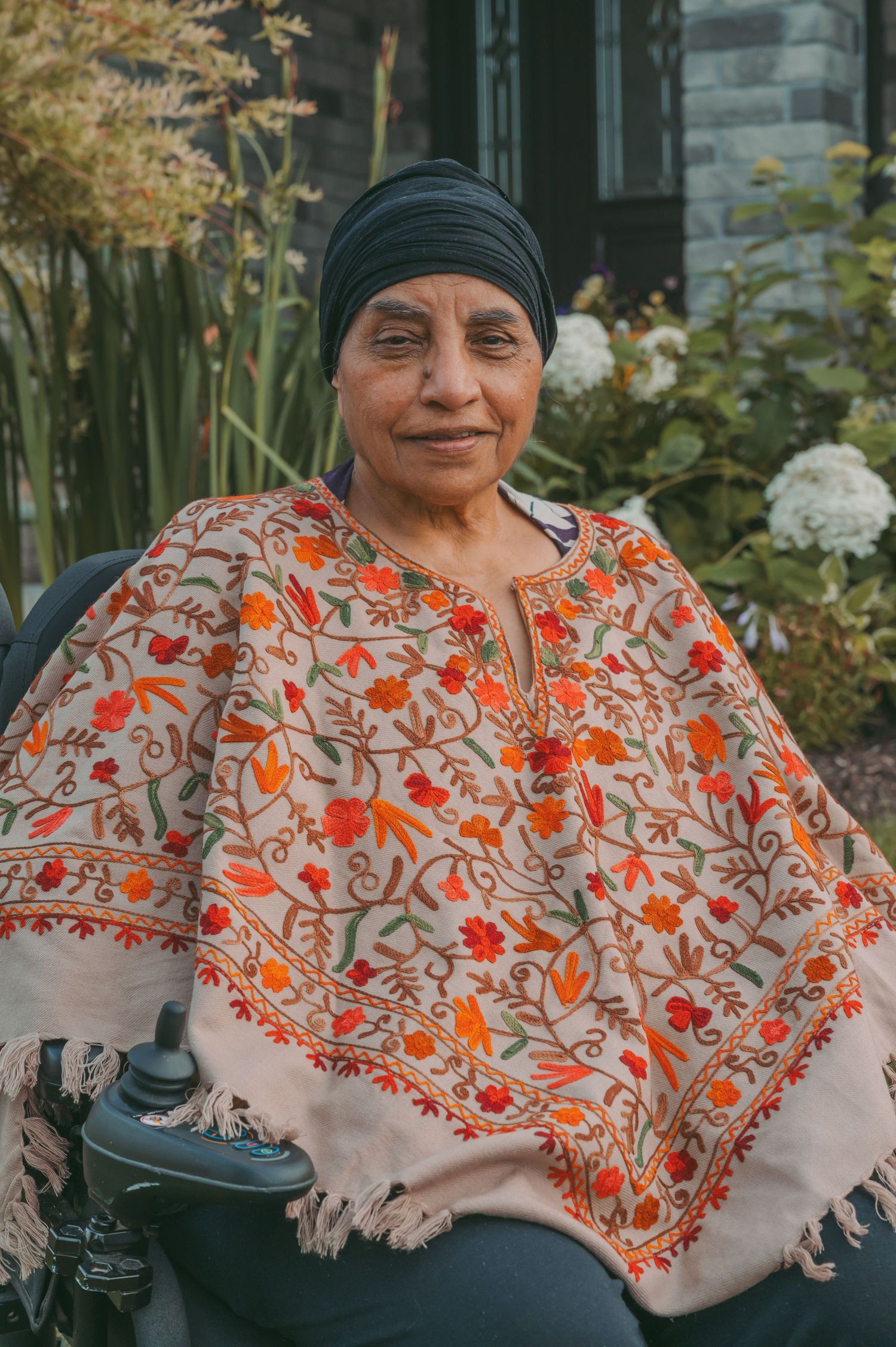 Someone wearing a vibrant orange and white floral shawl seated outdoors.