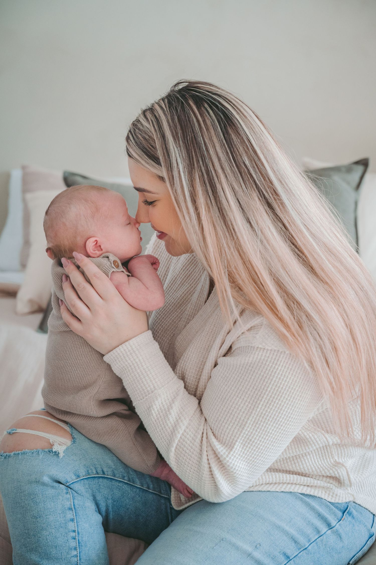 Intimate moment with newborn baby dressed in beige onesie being held close.