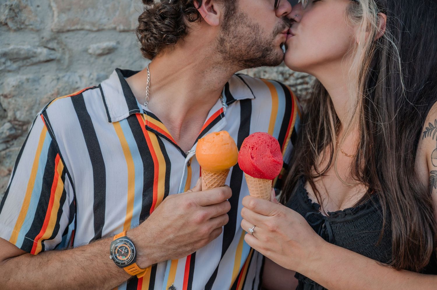 Two people enjoy colorful ice cream pops while sharing a romantic moment.