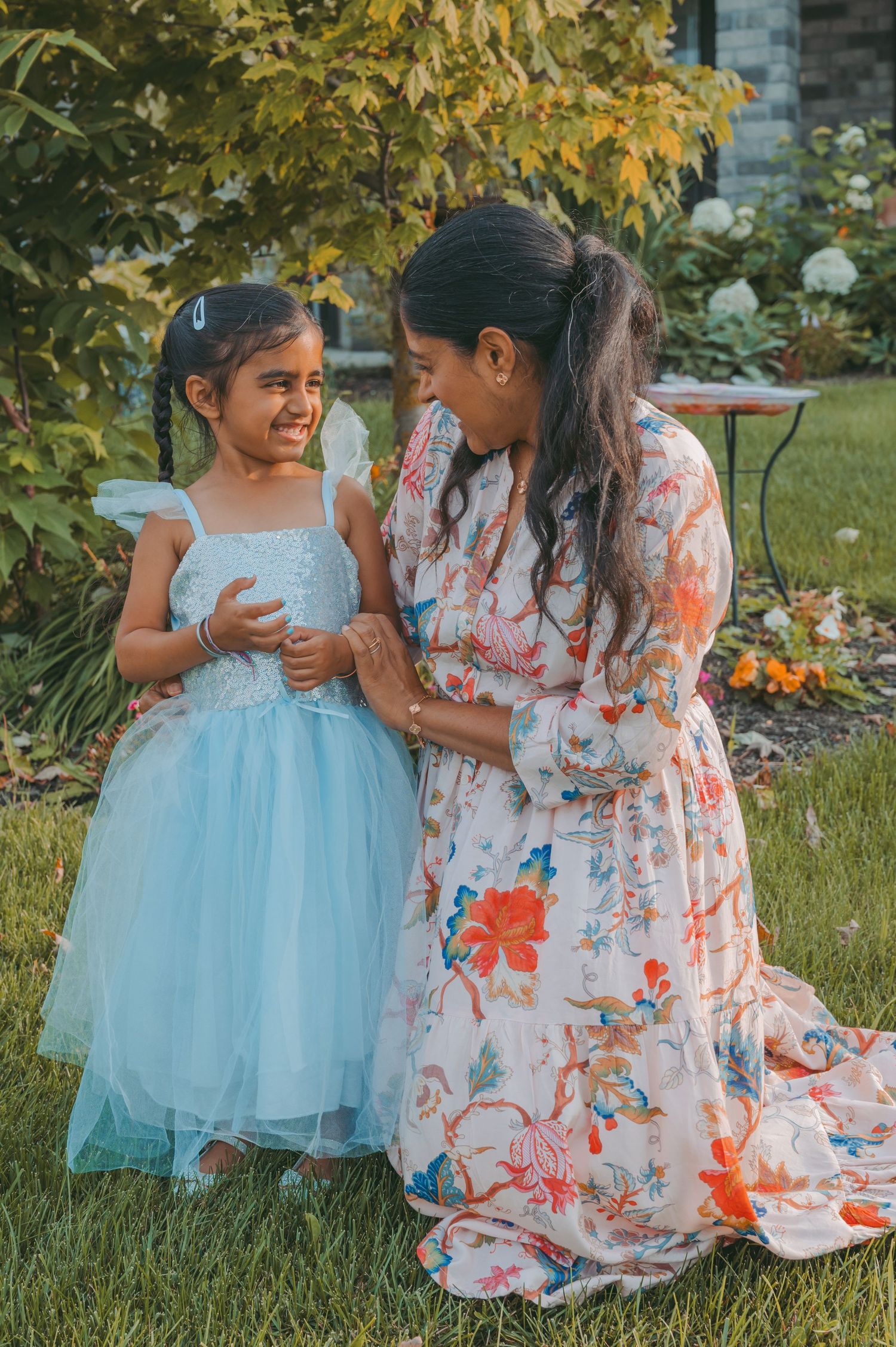 A heartwarming moment shared between people wearing floral dresses and blue tulle in a garden setting.