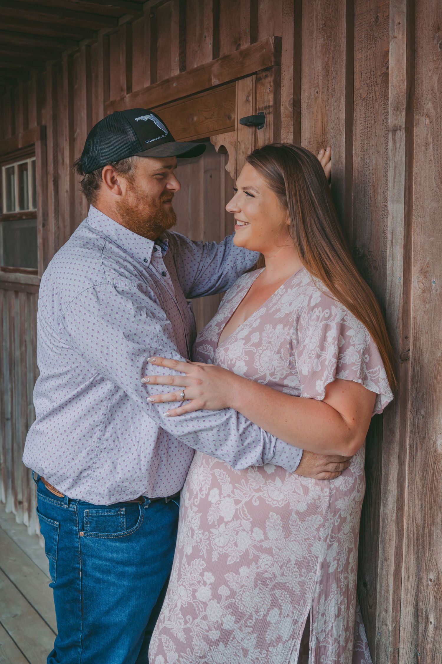 A couple shares a tender moment on a wooden porch during their countryside photoshoot.