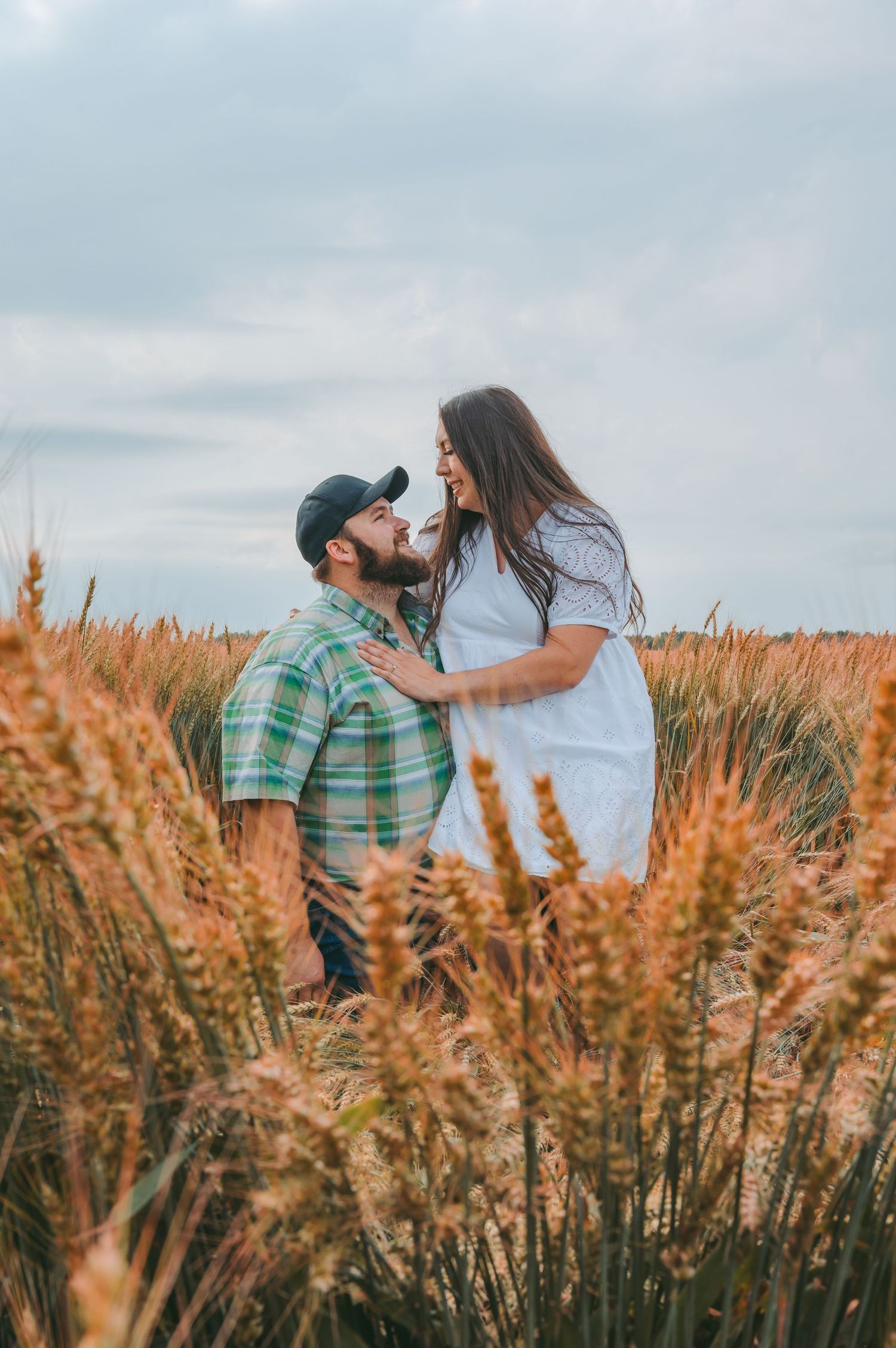 A tender moment captured between a couple surrounded by tall wheat stalks at dusk.