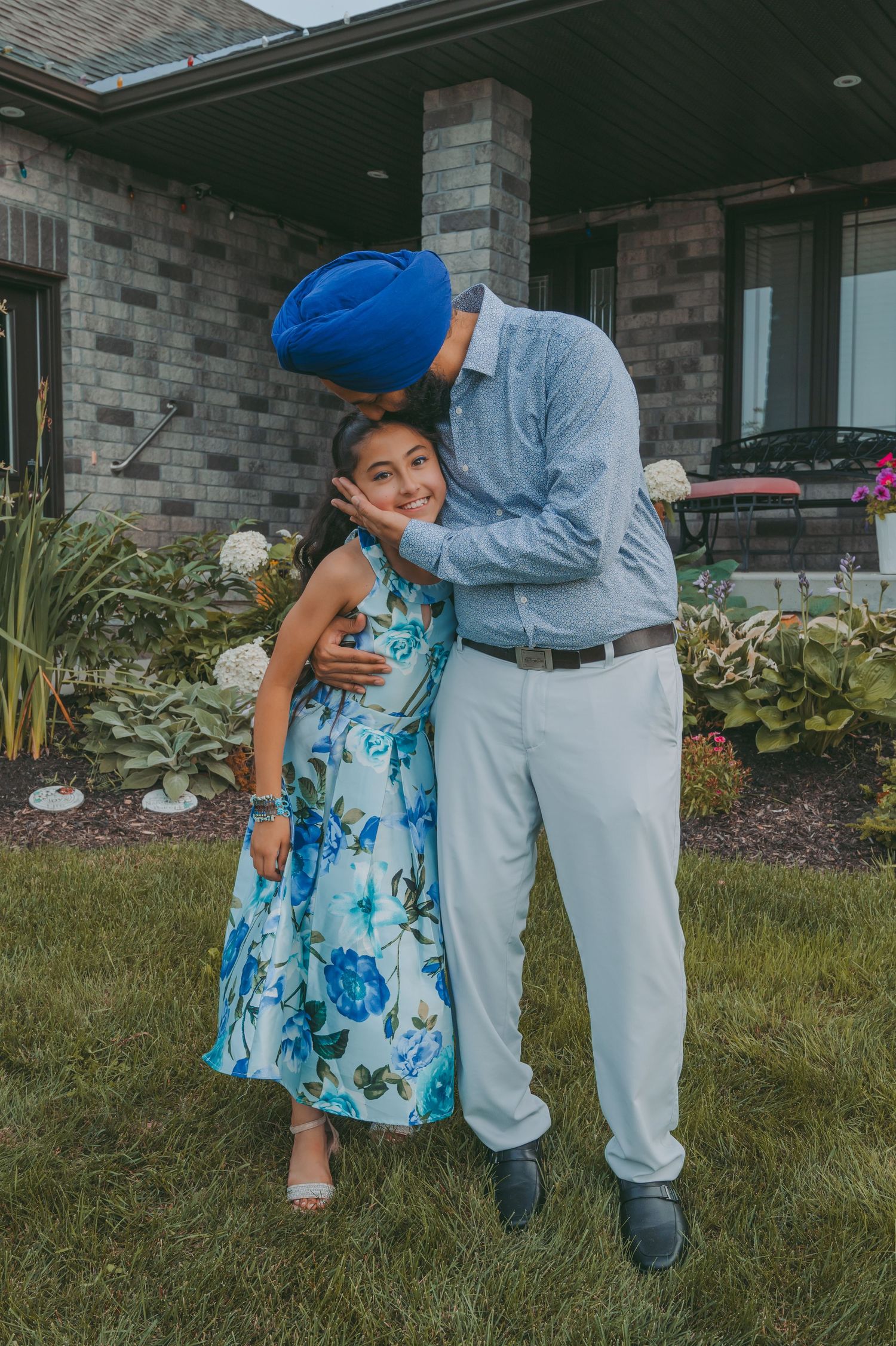 A playful interaction between people wearing blue and floral outfits on their lawn.