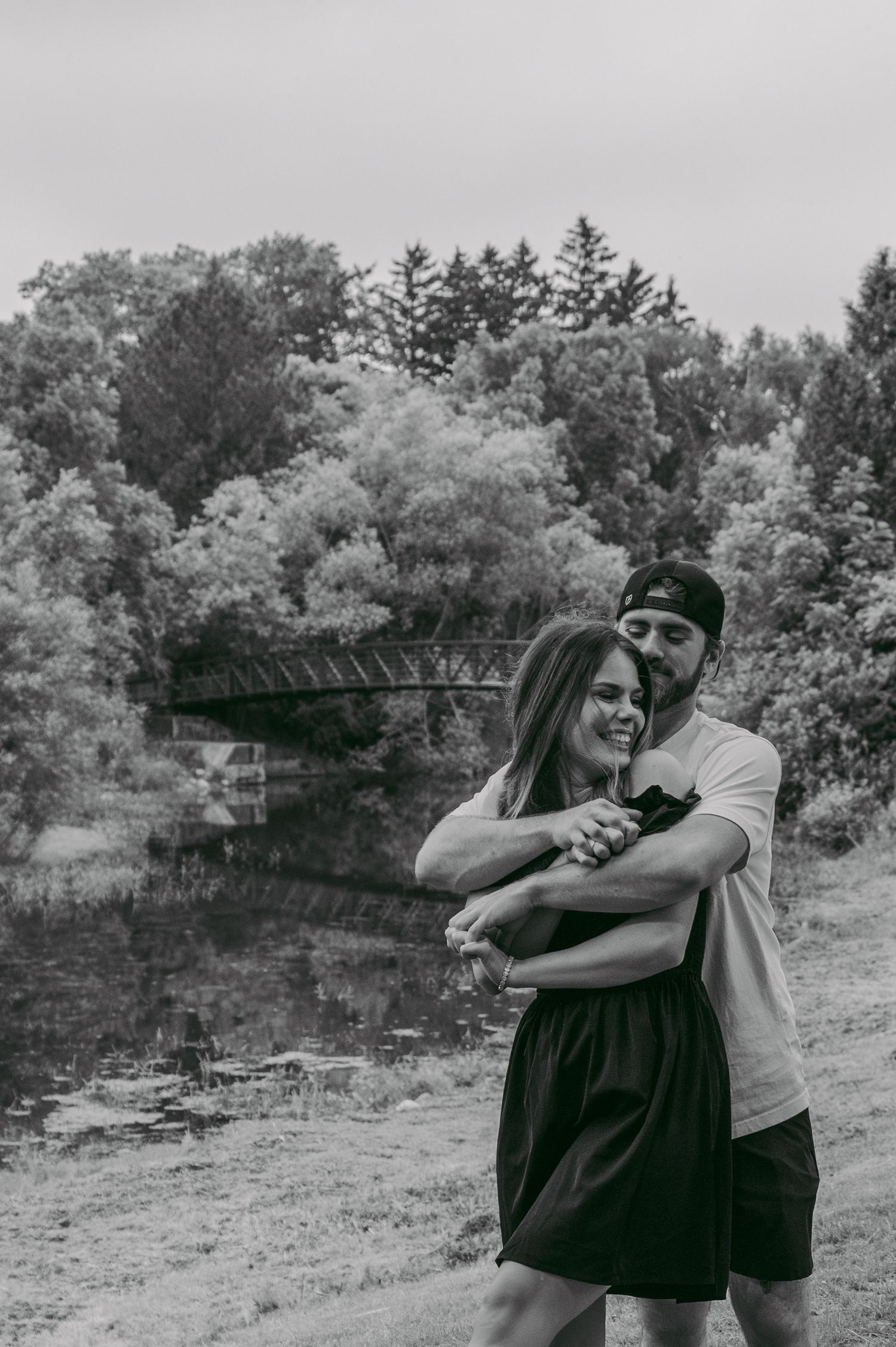 Black and white photos show a couple sharing tender moments and embraces in a natural outdoor setting.