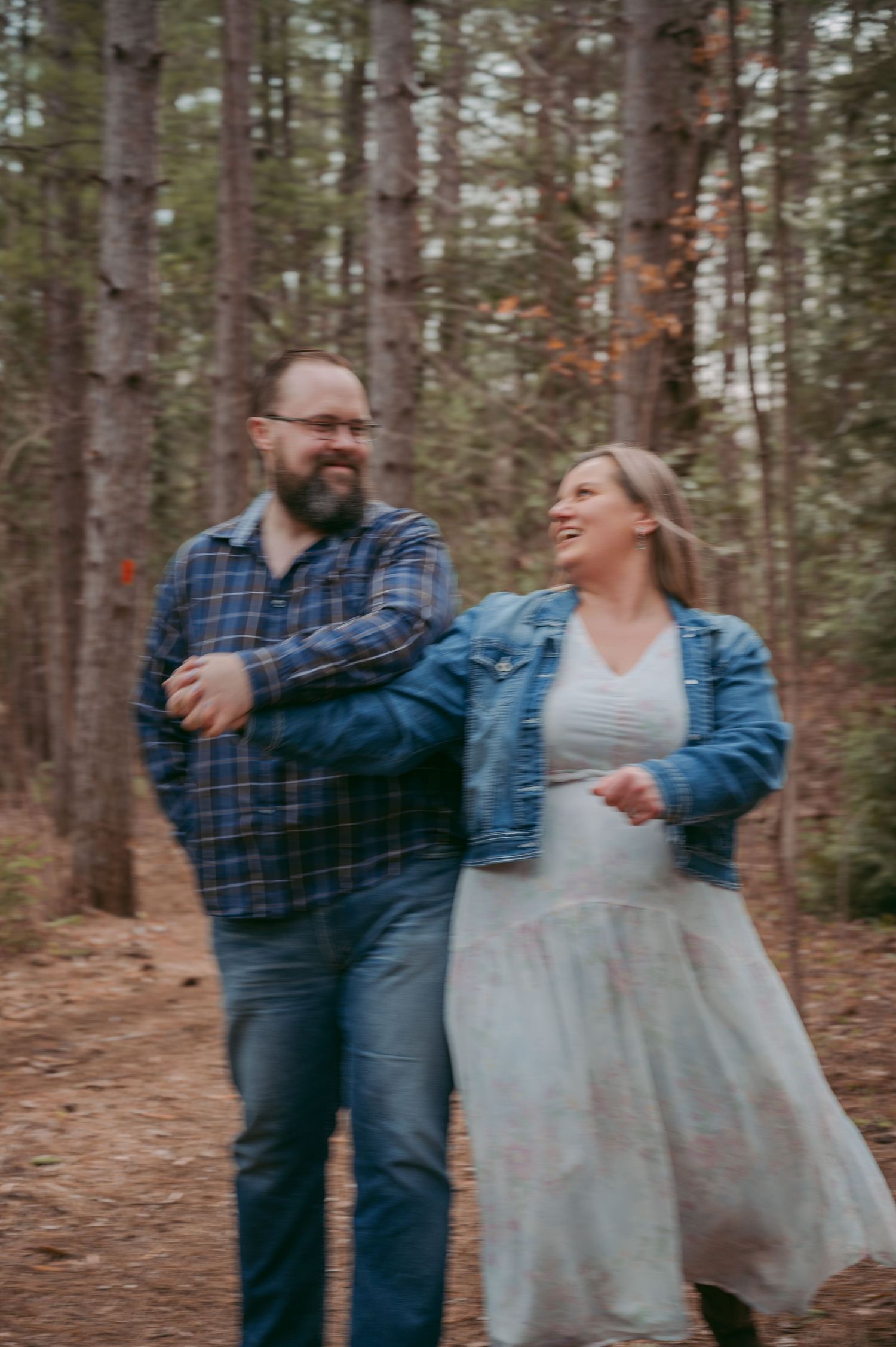 Joyful couple dancing and laughing together on a forest trail.