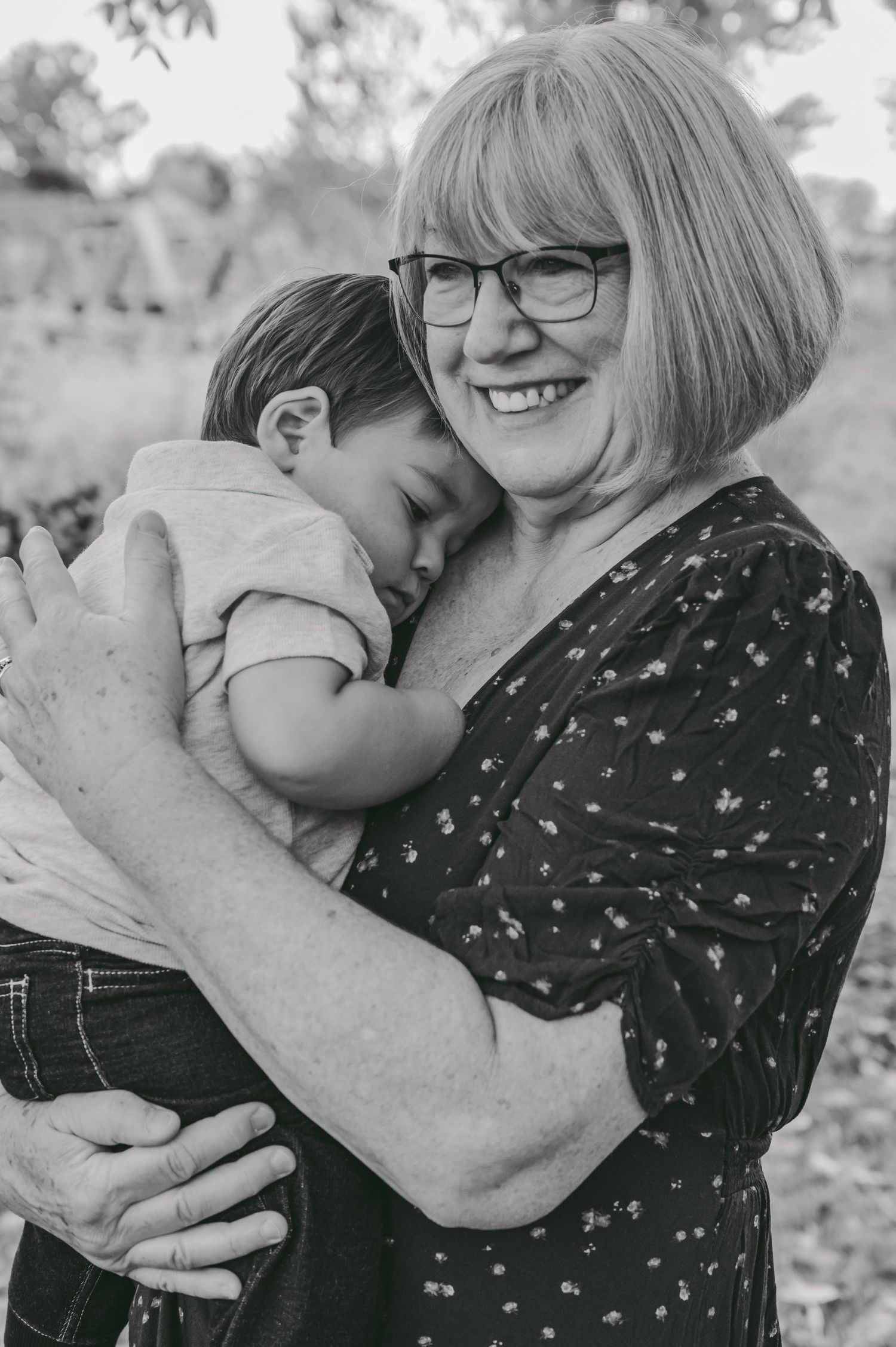 Black and white portrait showing tender moment between child and caregiver outdoors.