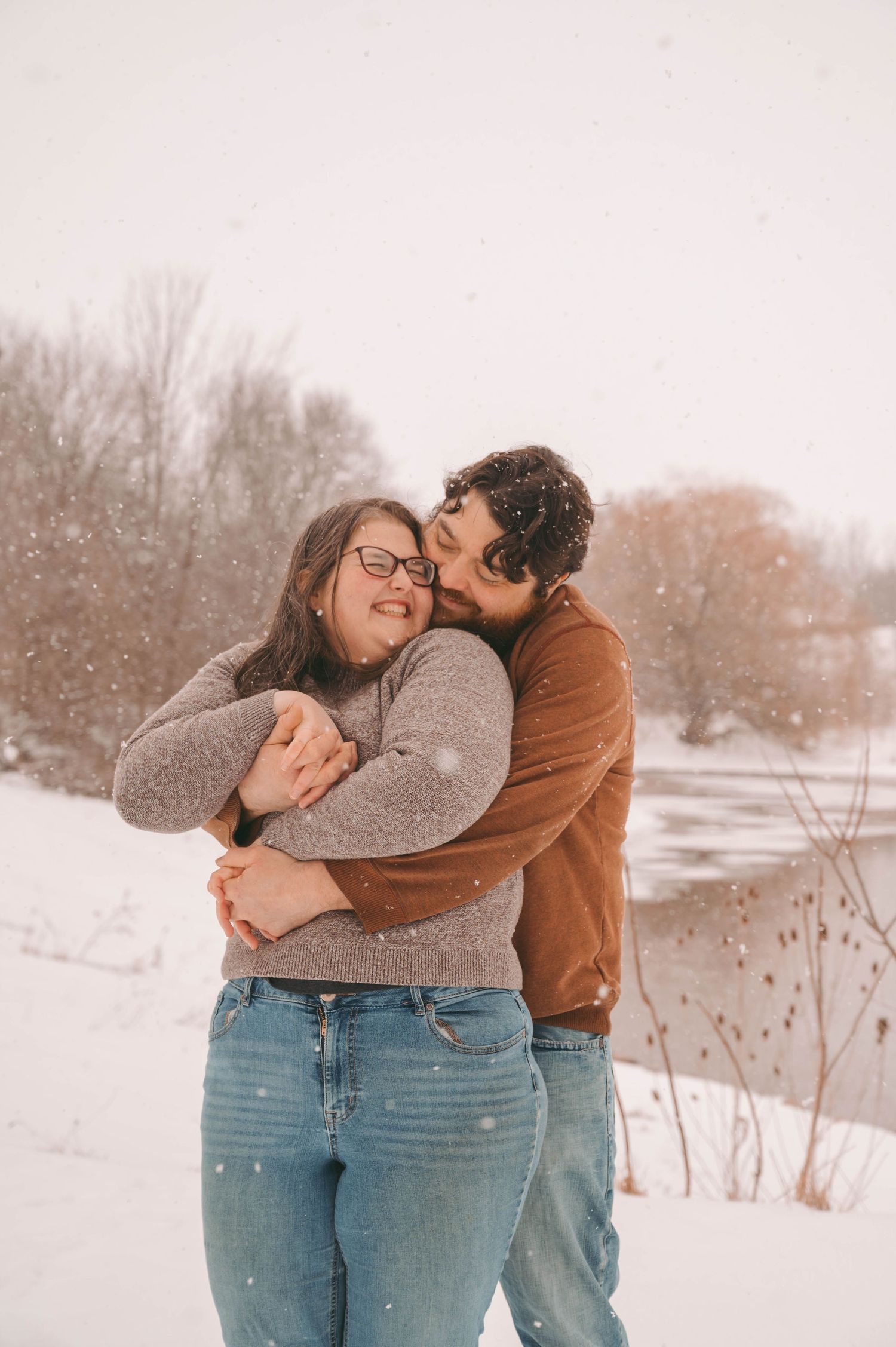 Couple sharing tender moment in snowy setting with winter scenery behind them.