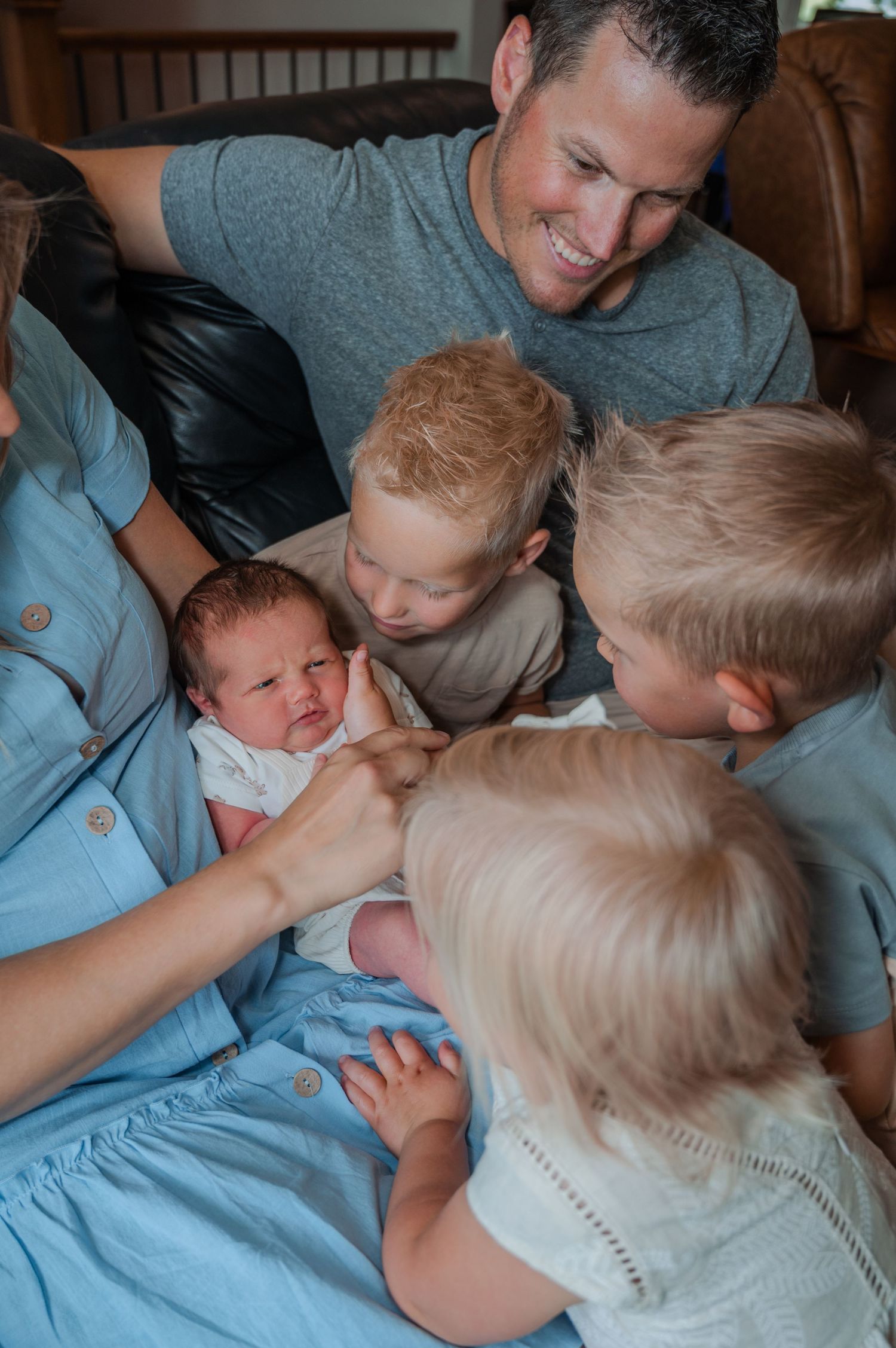 Candid family moment of siblings interacting playfully on a blue couch.