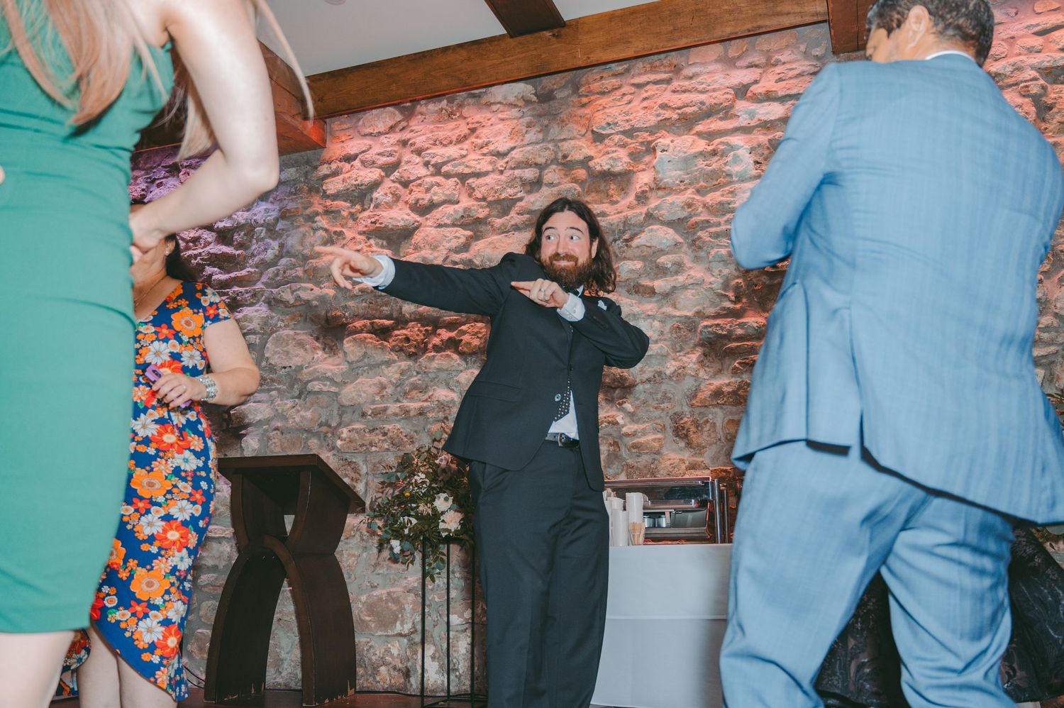 Wedding guests dancing and celebrating at a rustic brick venue.