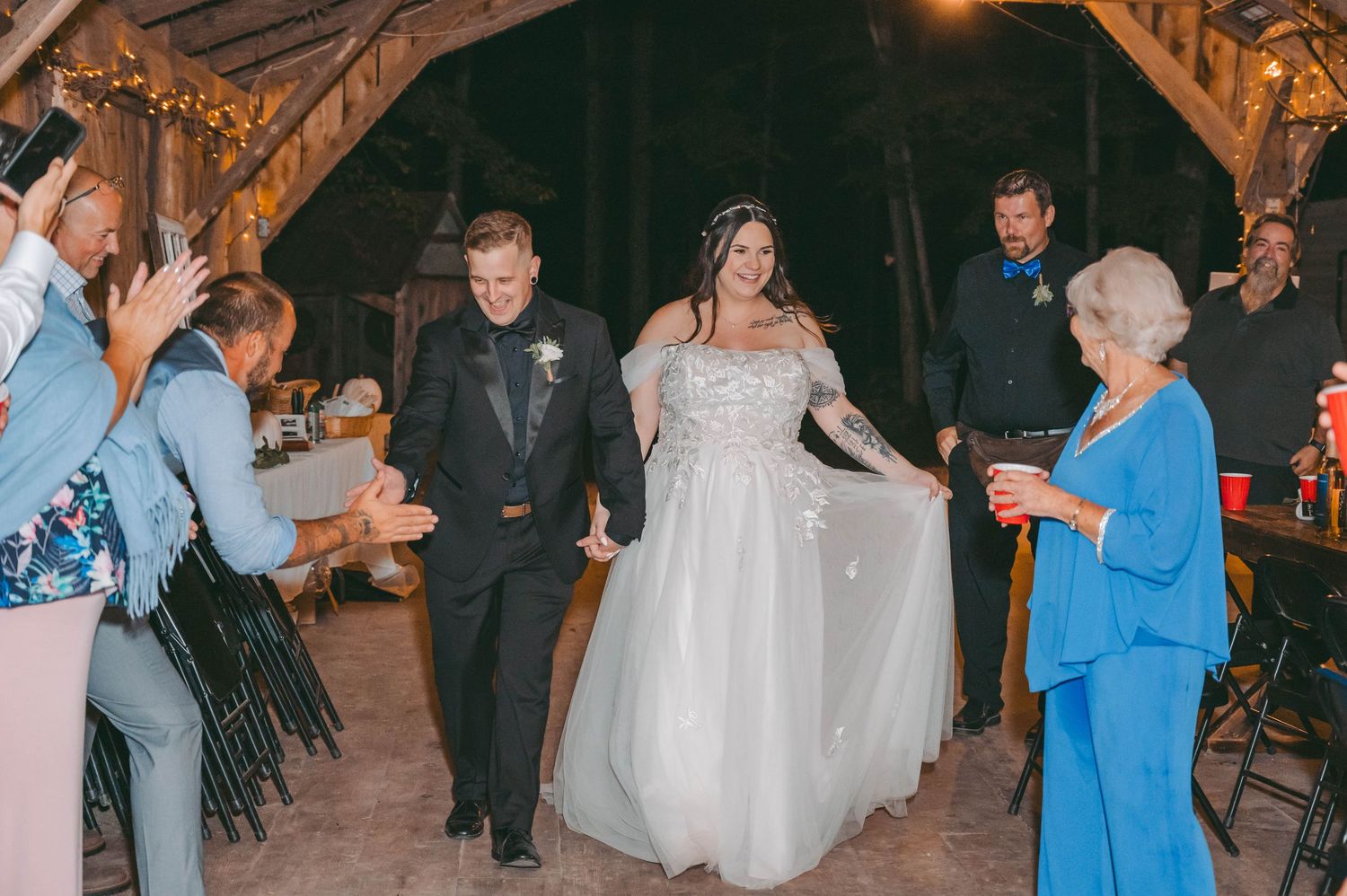 Wedding guests dancing together at an evening reception in a rustic barn venue.