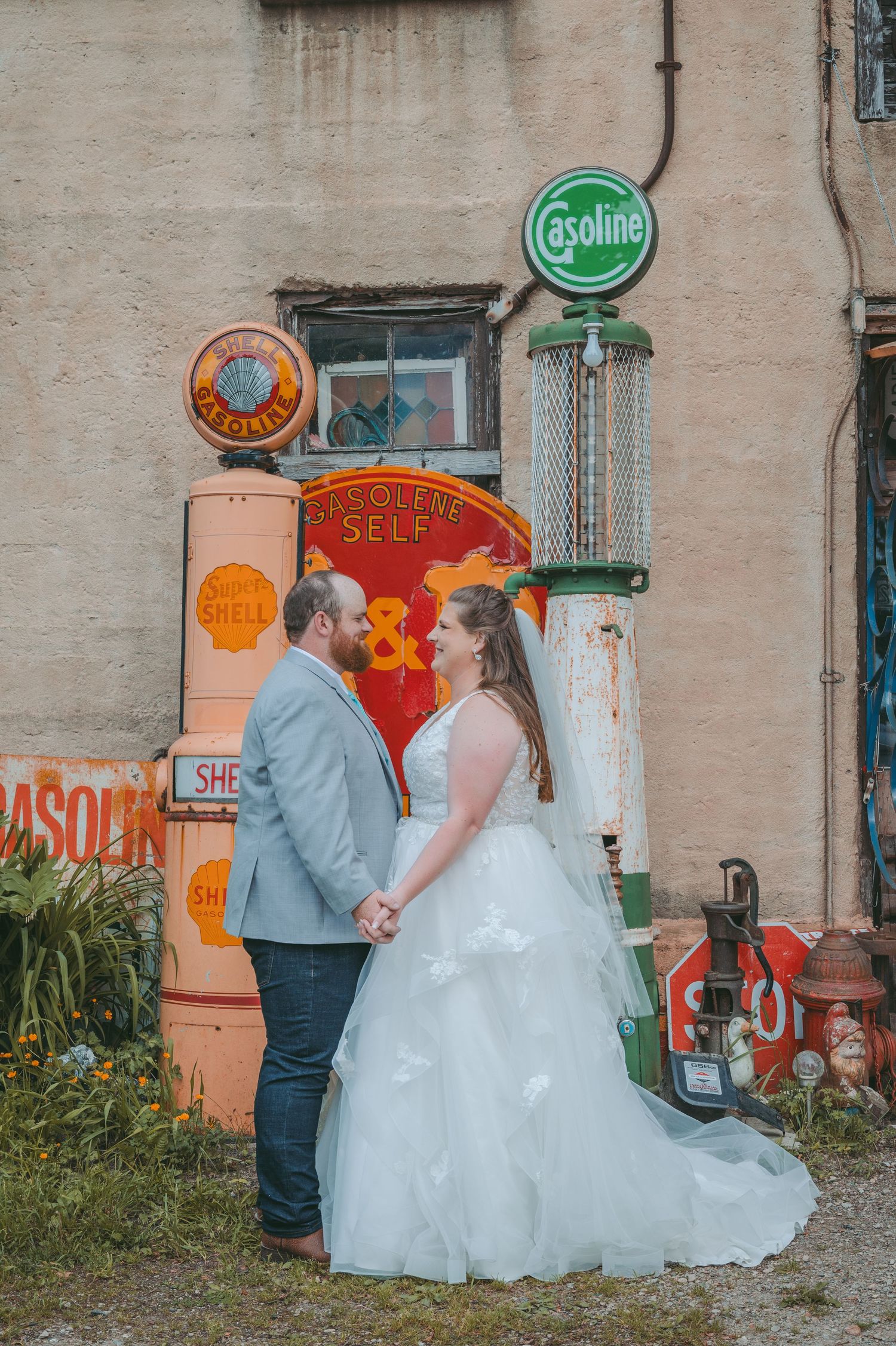 Wedding couple poses against urban wall with vintage signs and industrial backdrop.