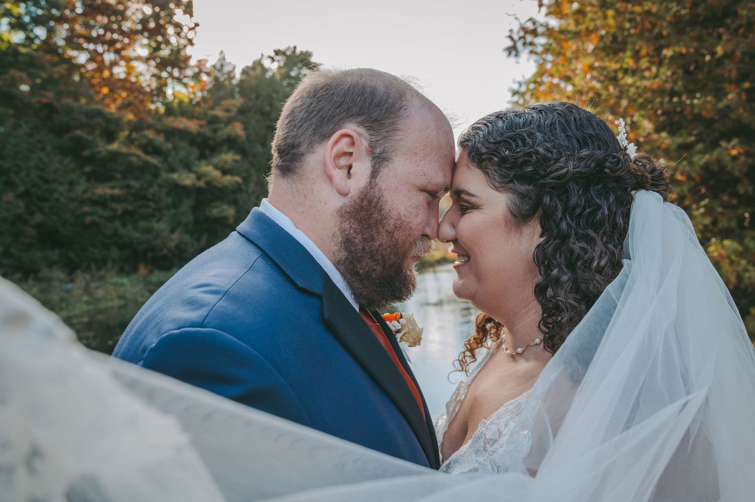 Intimate close-up photo of newlyweds sharing tender moment during outdoor autumn wedding.