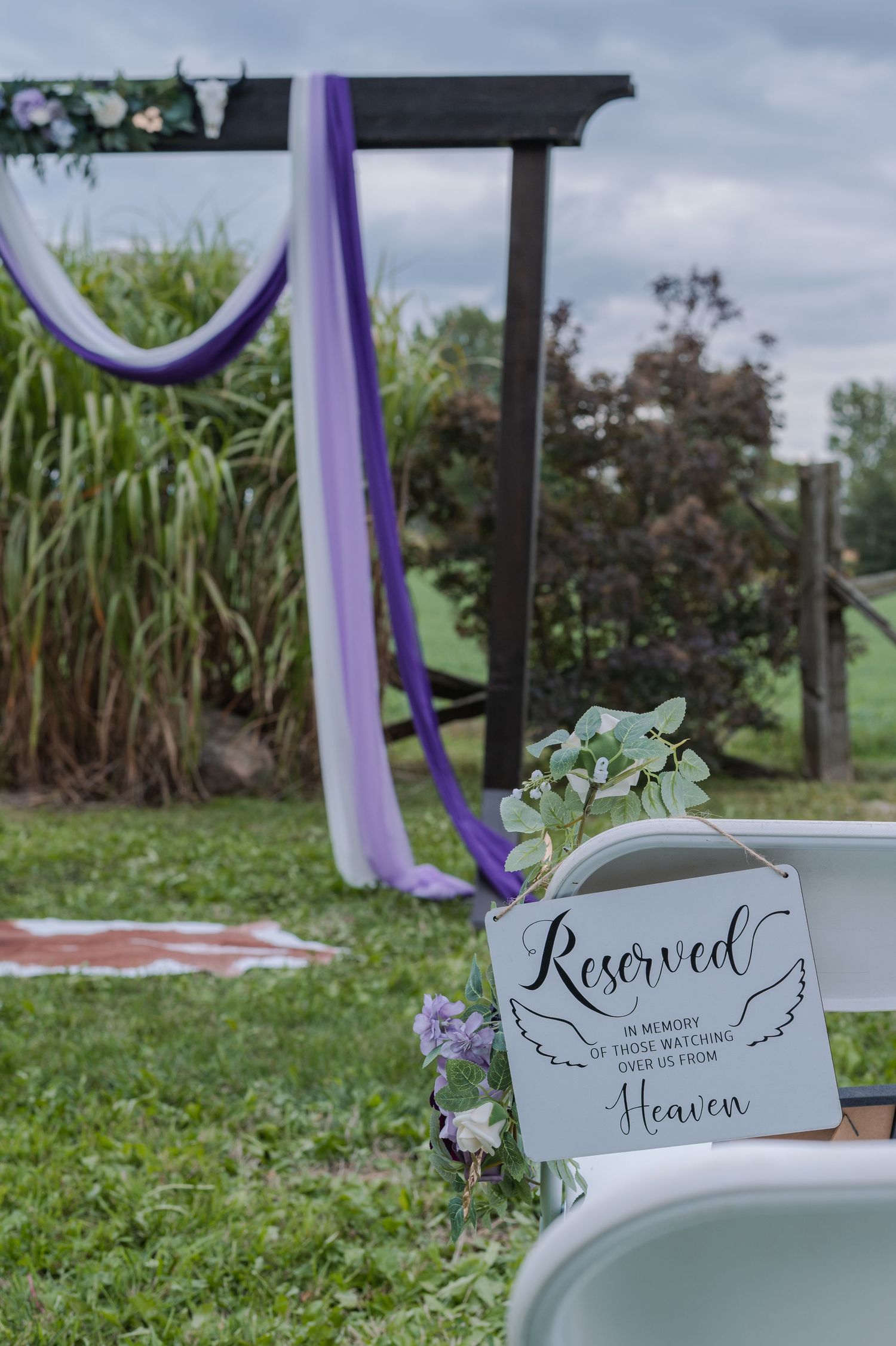 Memorial chairs with purple ribbons and 'Reserved for Heaven' signs honor loved ones at an outdoor ceremony.