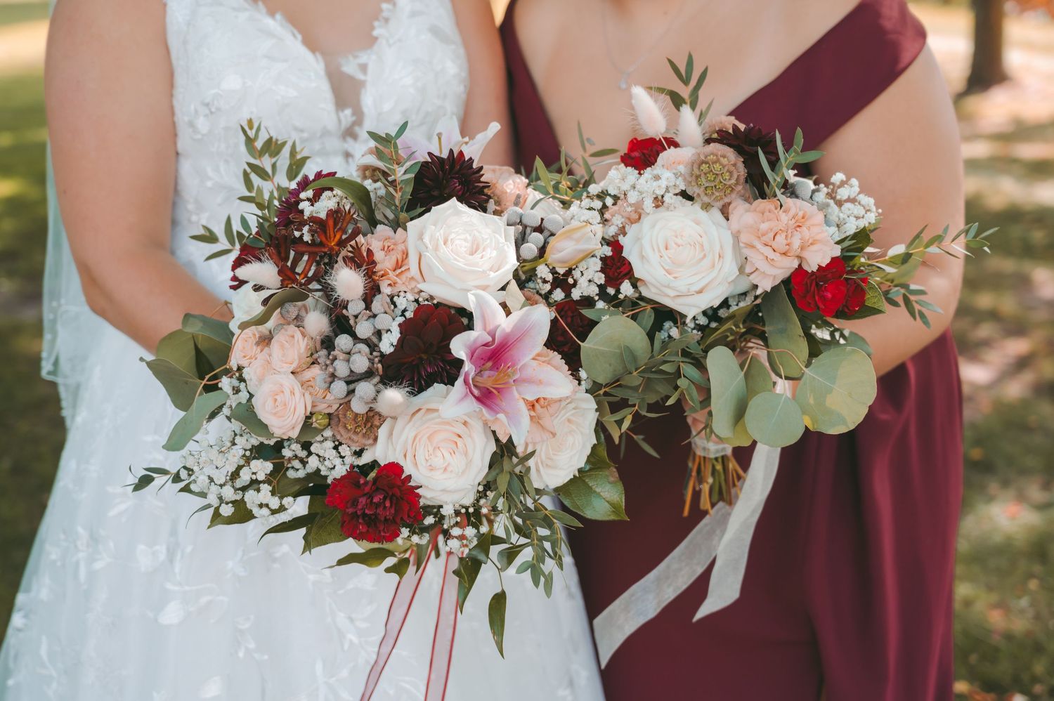 Wedding bouquets featuring burgundy and pink roses with greenery.