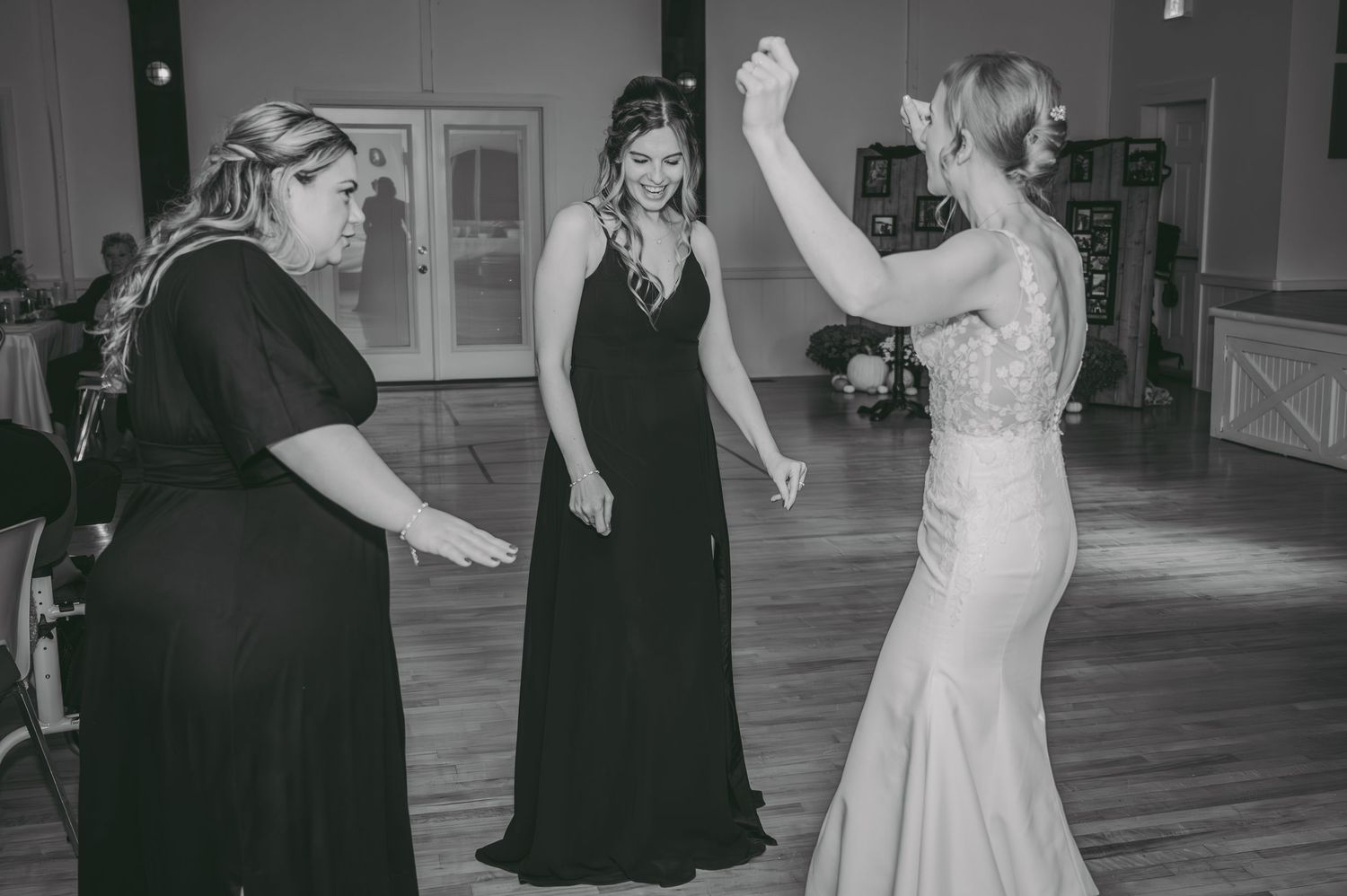 Black and white candid shot of guests and bride dancing and celebrating at a wedding reception.