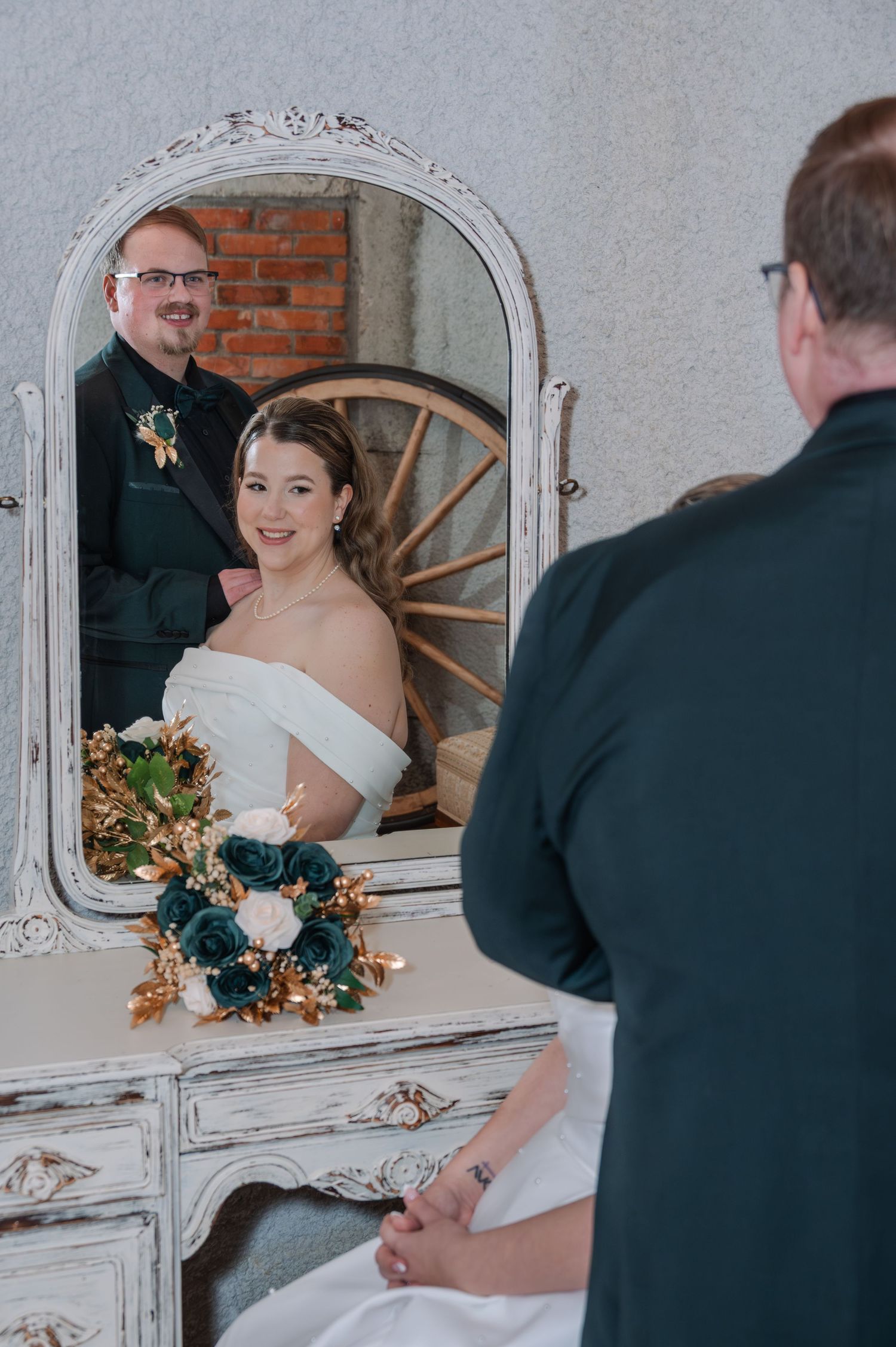 A bride and groom share intimate moments in front of an ornate vintage mirror during their wedding photoshoot.