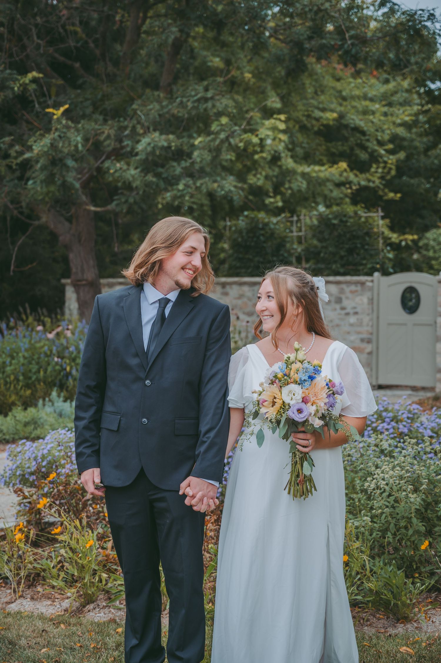 Candid wedding photos show couple sharing happy moments among garden flowers.