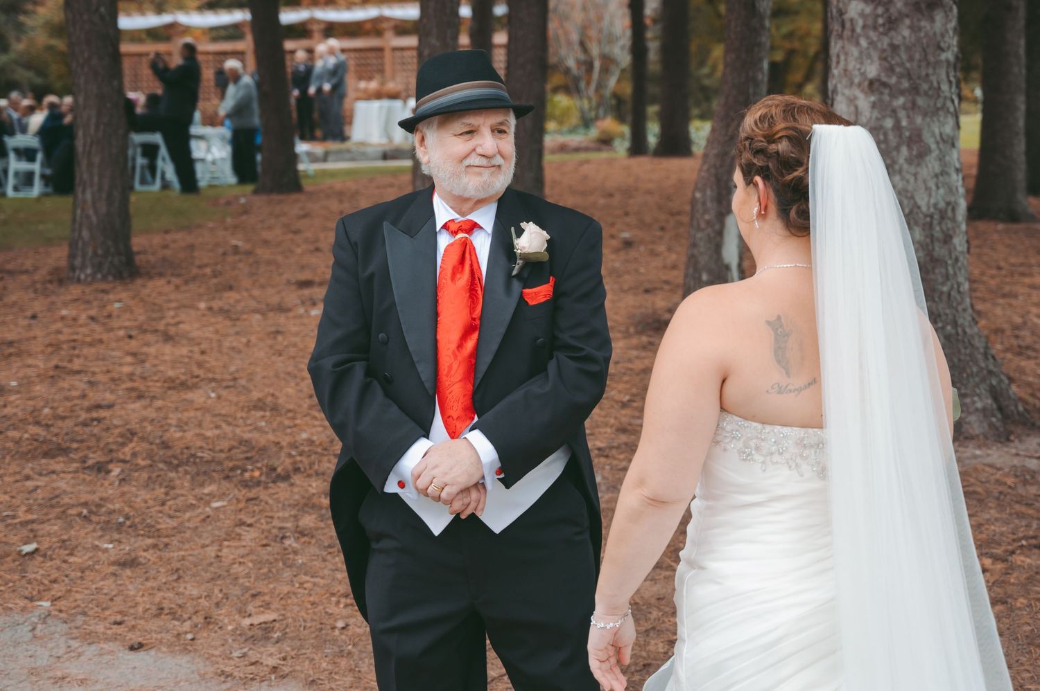 A formal outdoor wedding portrait in an autumn setting with pine trees.