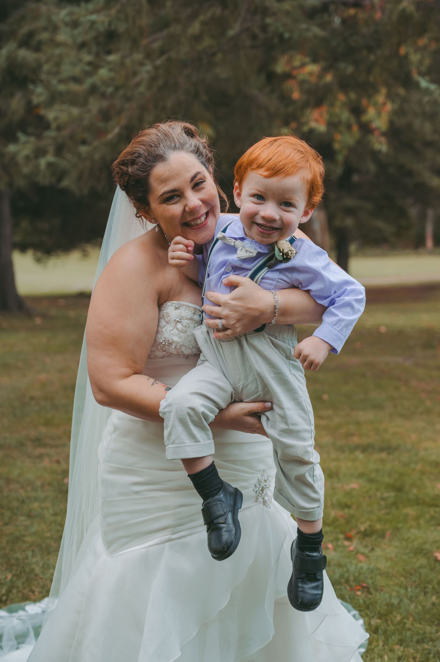 Heartwarming moment between bride and young ring bearer in suspenders.