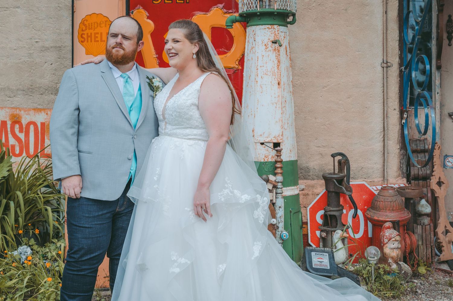 A couple shares a romantic moment outside a rustic building with colorful murals and vintage decor.
