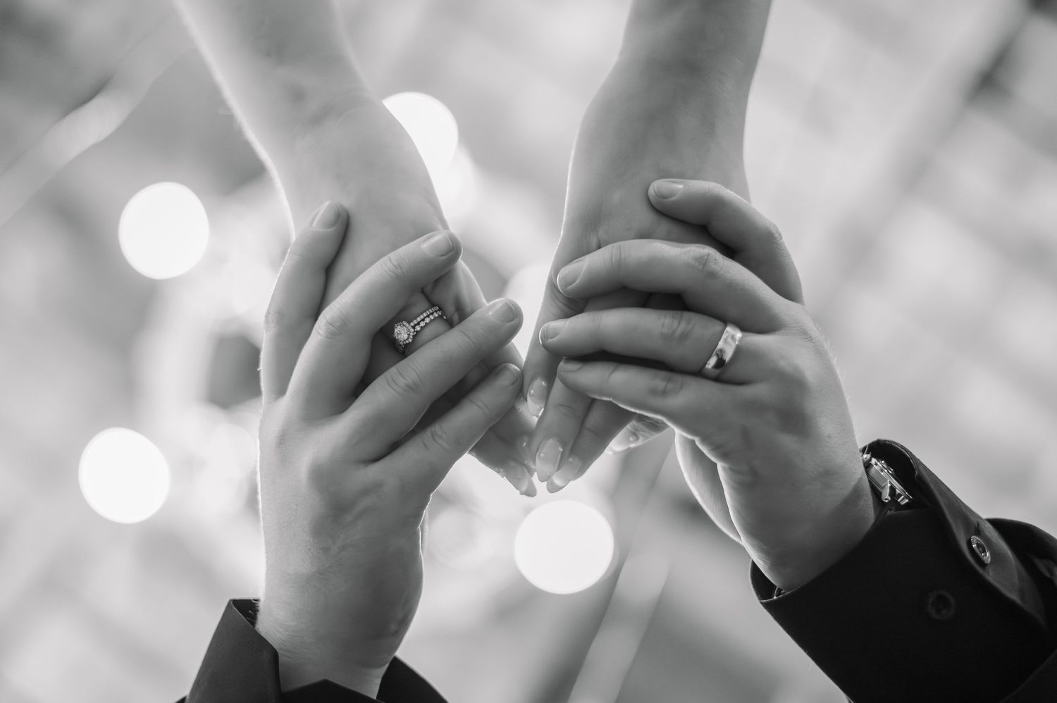 A black and white close-up photo of hands holding a mobile phone against a blurred bokeh background.