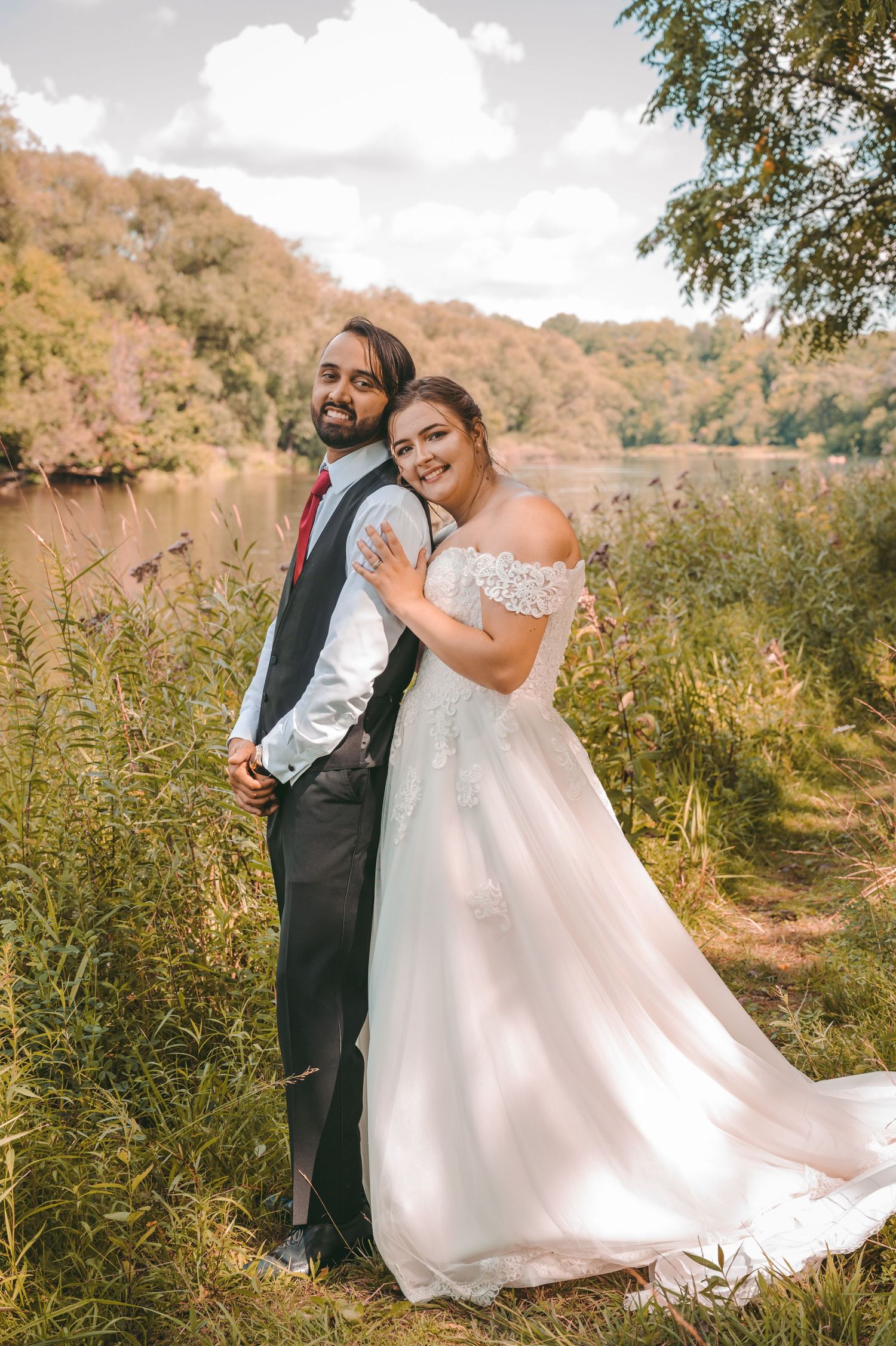 A romantic first look sequence in nature showing a couple in wedding attire embracing among tall grass and trees.