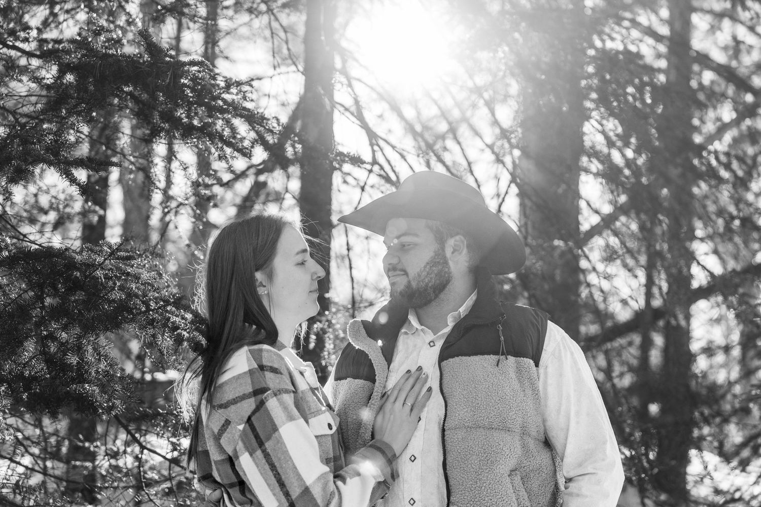 Multiple candid shots of a couple embracing and sharing tender moments against a sunlit forest backdrop.