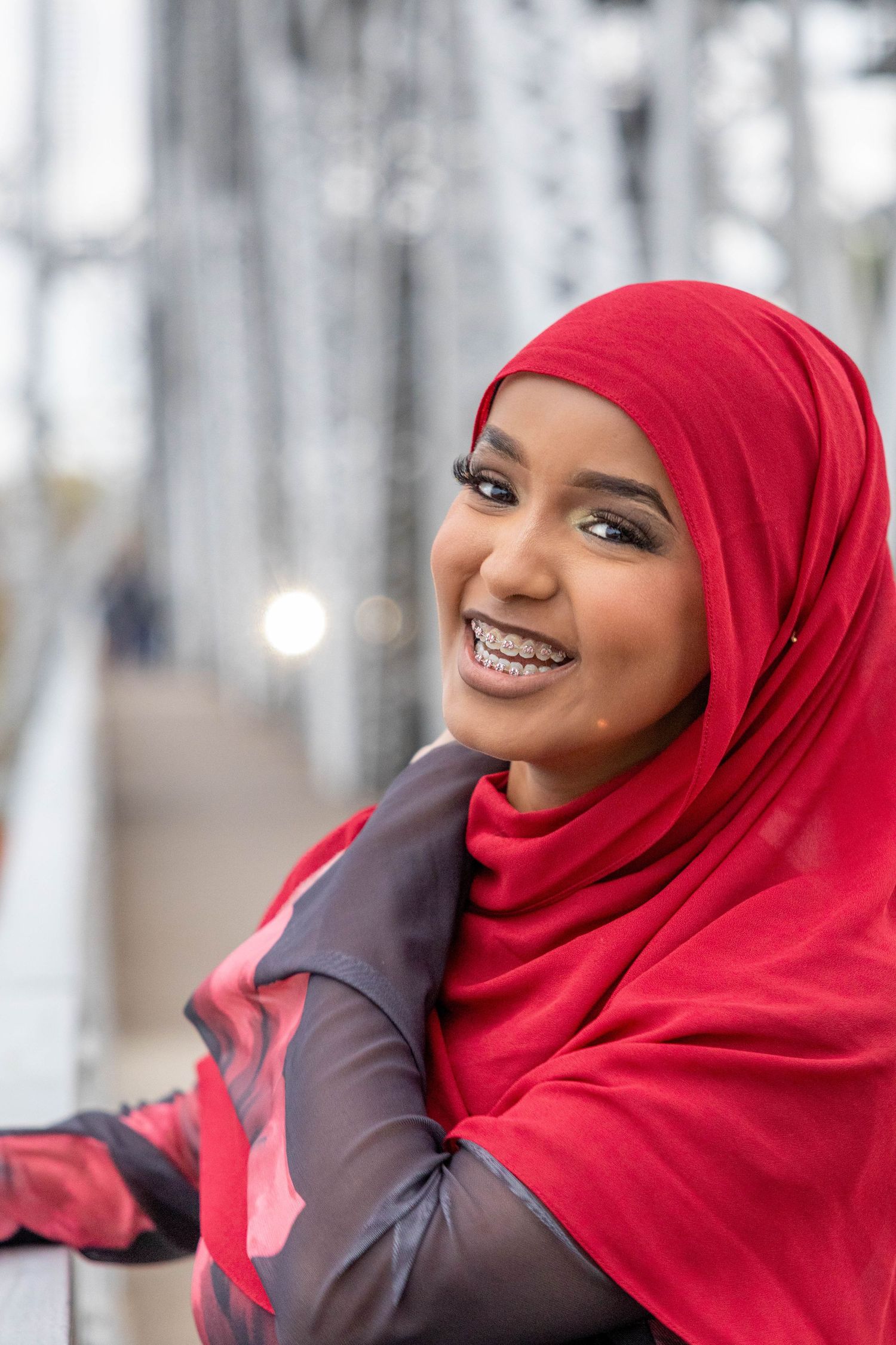 Three photos show a person wearing a bright red hijab and dark top smiling warmly at the camera.