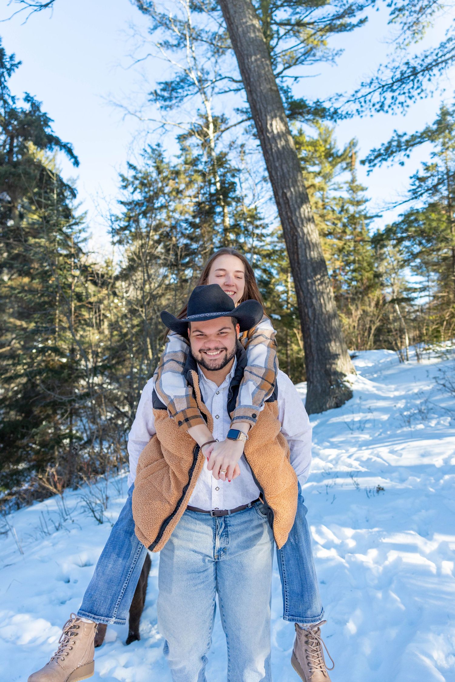 Candid winter engagement photos showing joyful moments in a snowy forest setting.