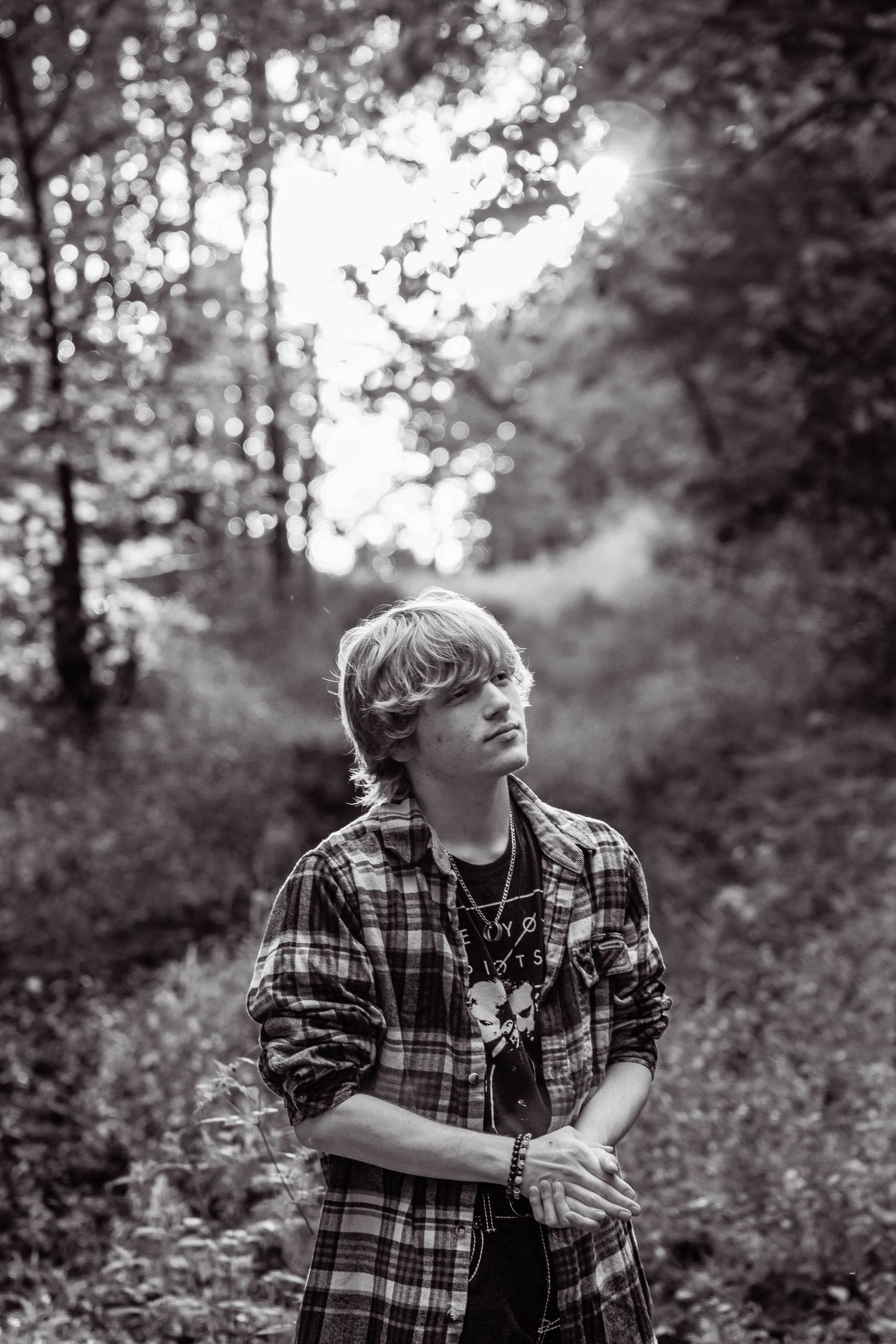 Black and white photo series of a person in a plaid shirt sitting outdoors surrounded by trees and foliage.