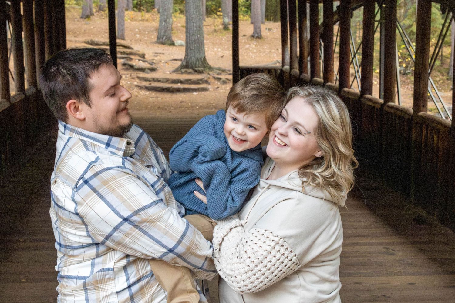 A family shares a playful moment together on a wooden covered bridge during an outdoor photo session.
