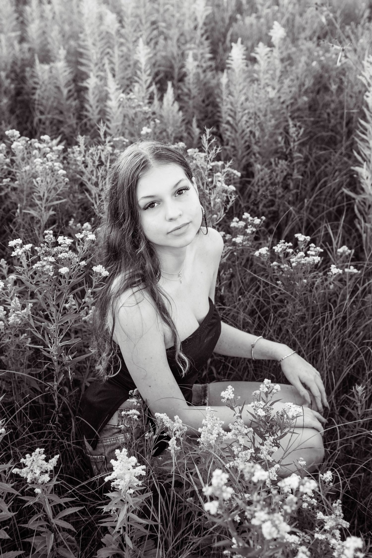 A black and white portrait series shows a woman posing gracefully among blooming wildflowers in a garden setting.