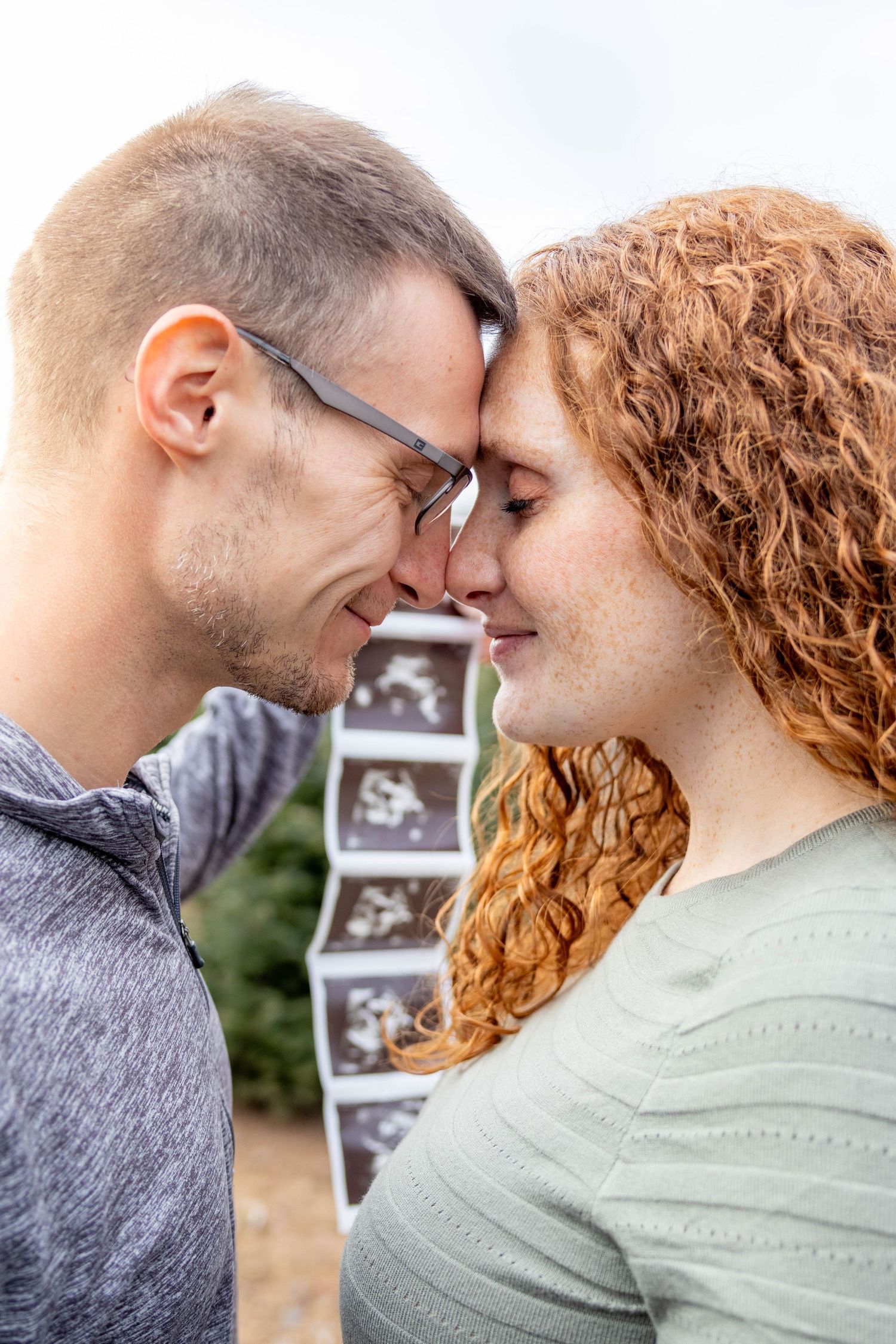 Romantic couple sharing tender moments in a series of close-up photos while holding ultrasound images in the background.