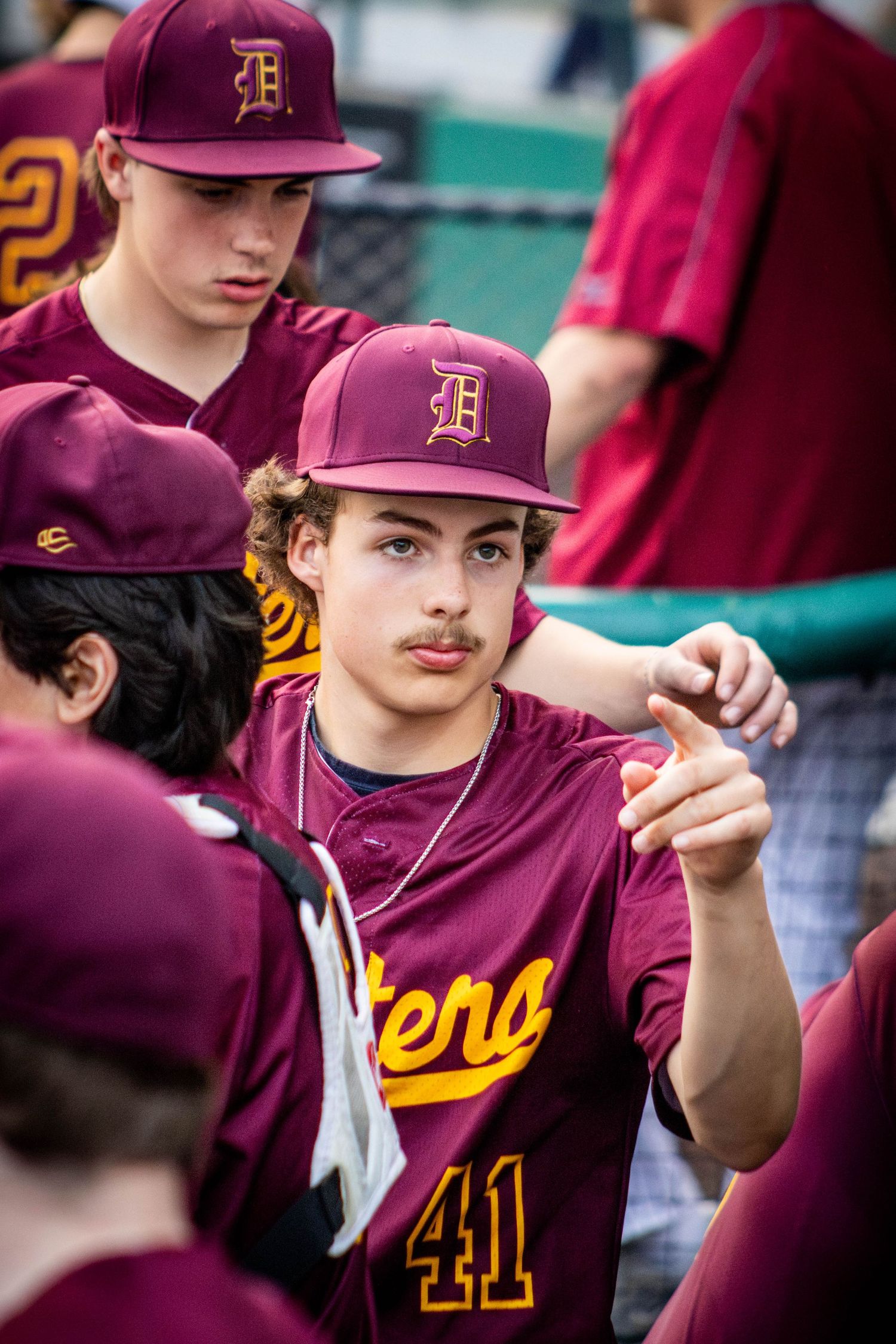 Baseball player in maroon Arizona State University uniform gestures to teammates from the dugout during a game.