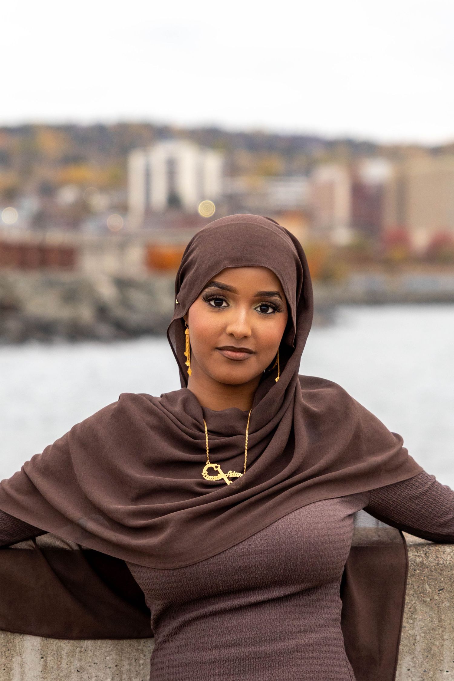 A collection of portraits featuring someone wearing a brown hijab and necklace against a waterfront setting.